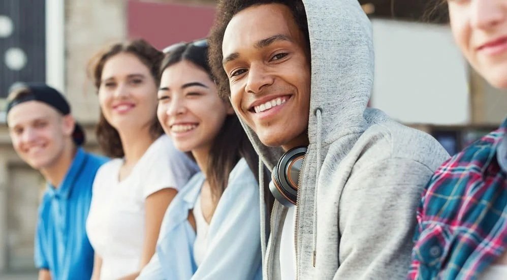 A group of young people standing outdoors, smiling at the camera.