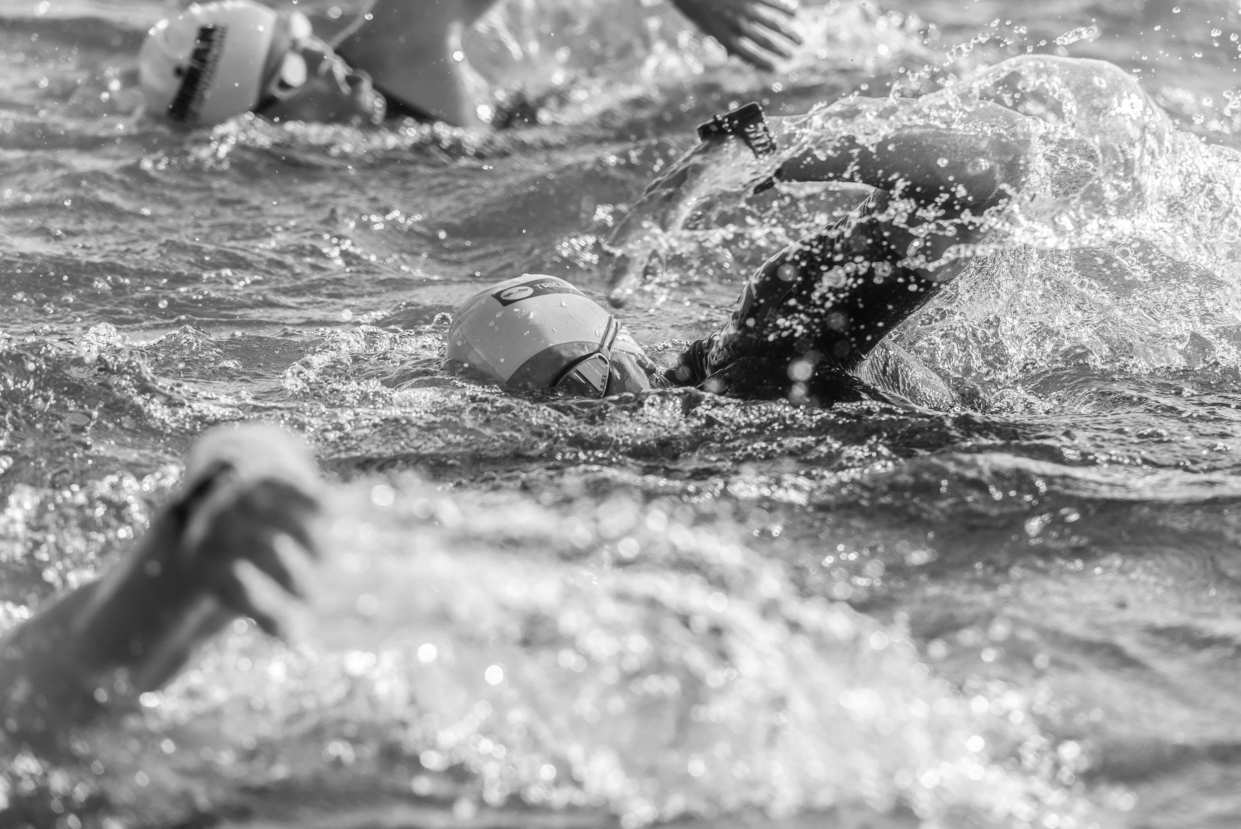 Black and white closeup image of an athlete swimming in a pool.