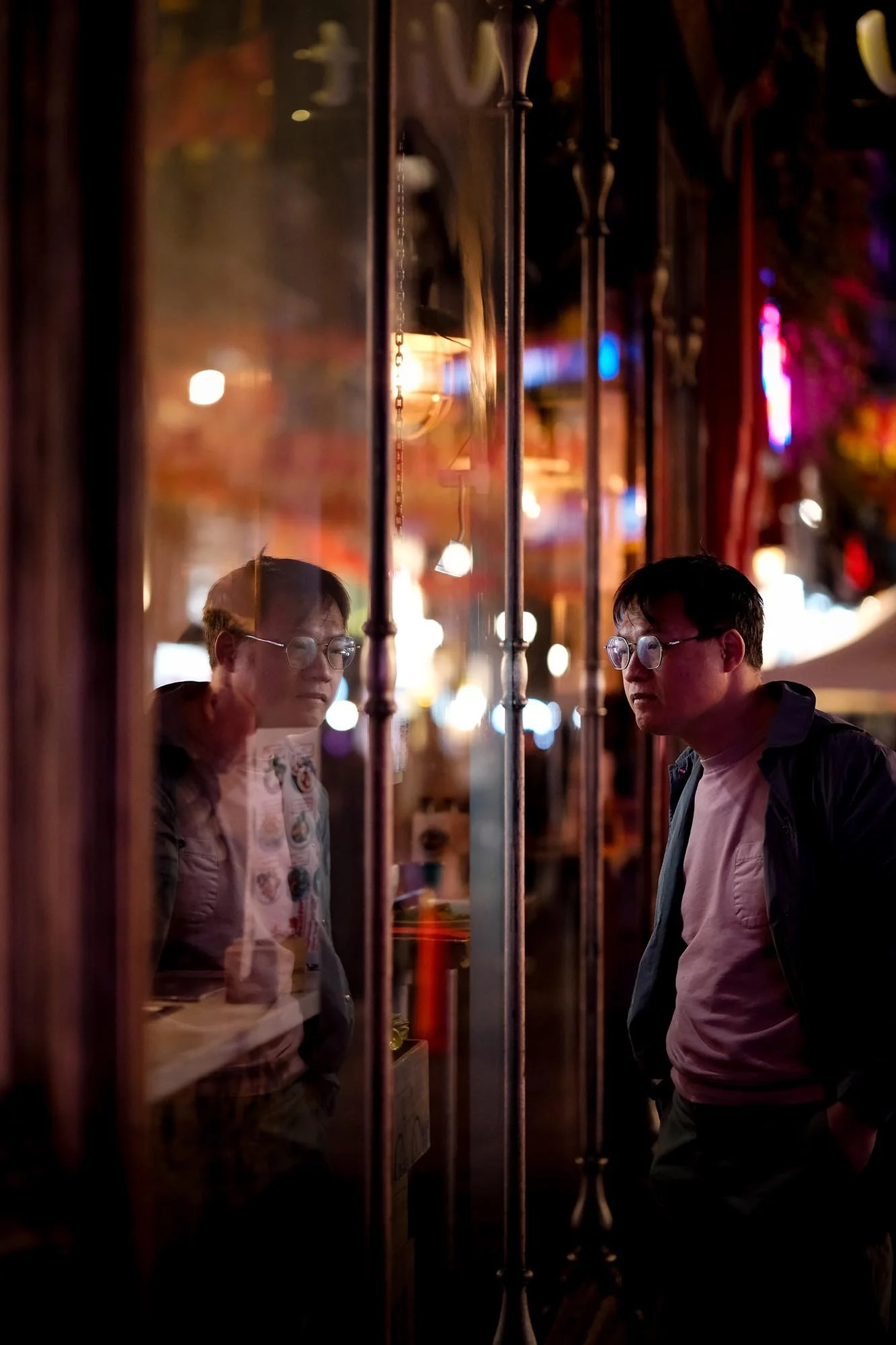 Man reflected in a shop window at night in a moody street photography scene