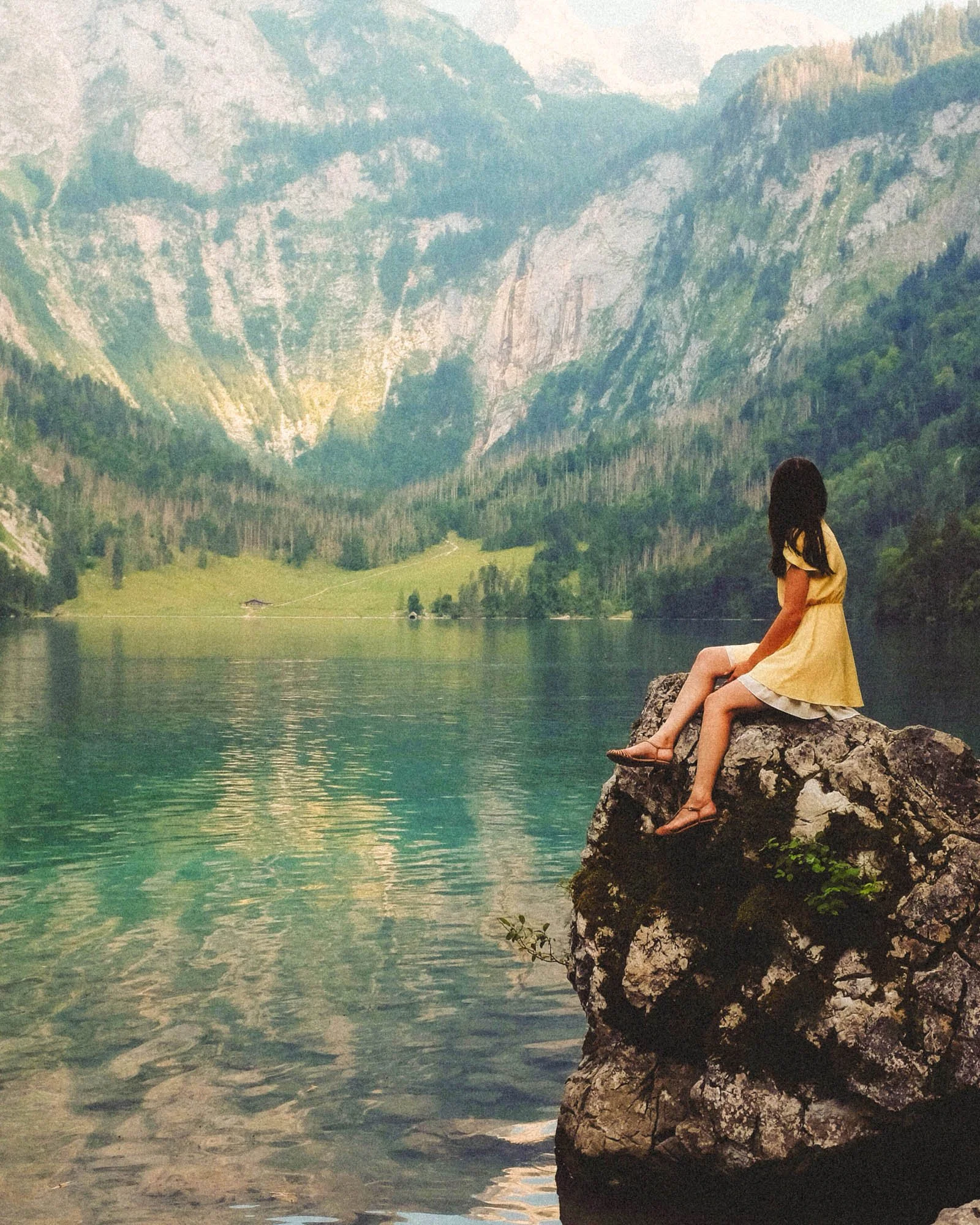 Woman sitting by a mountain lake and cliffs in a photo after Lightroom presets have been applied