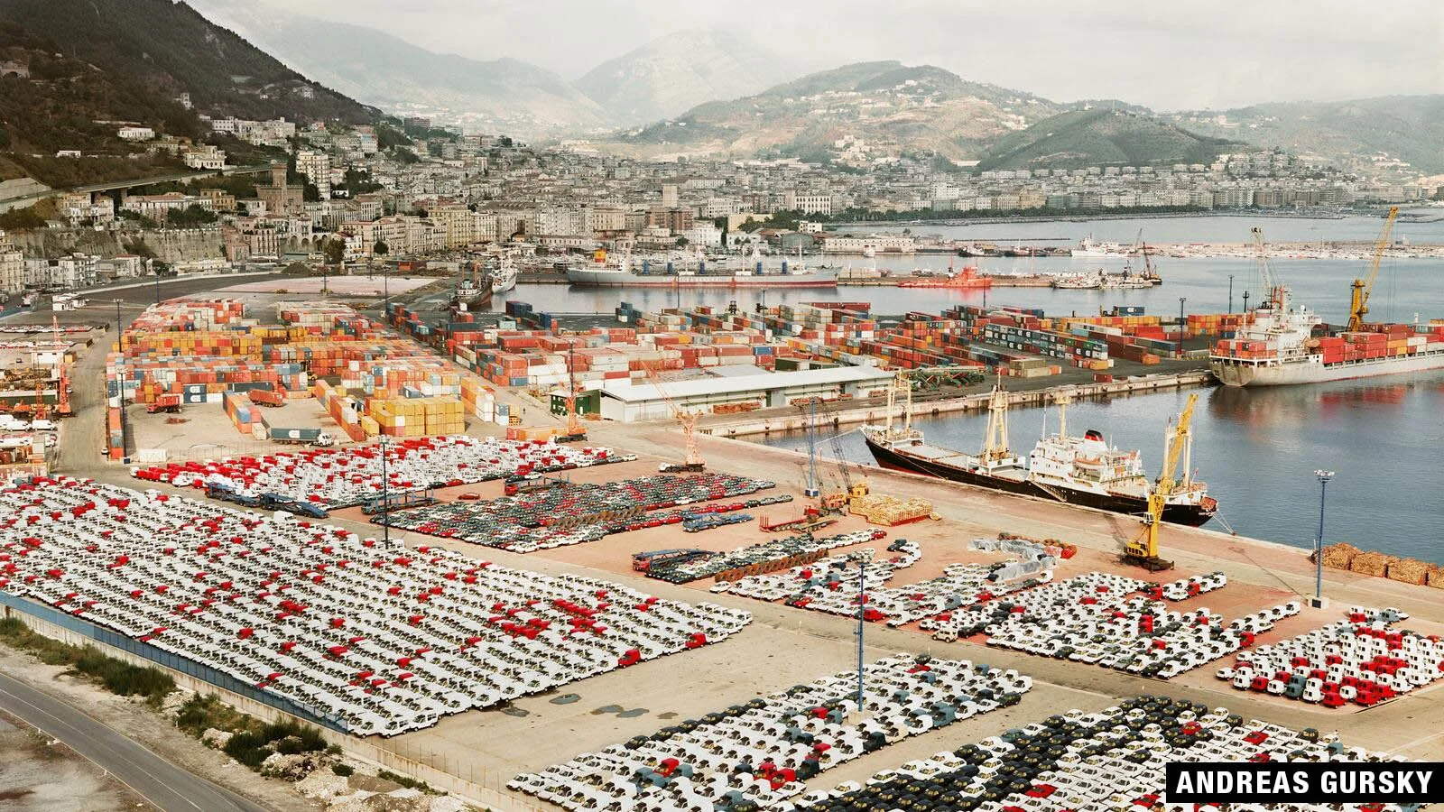 Aerial view of Salerno port with containers, cars, ships, and city.
