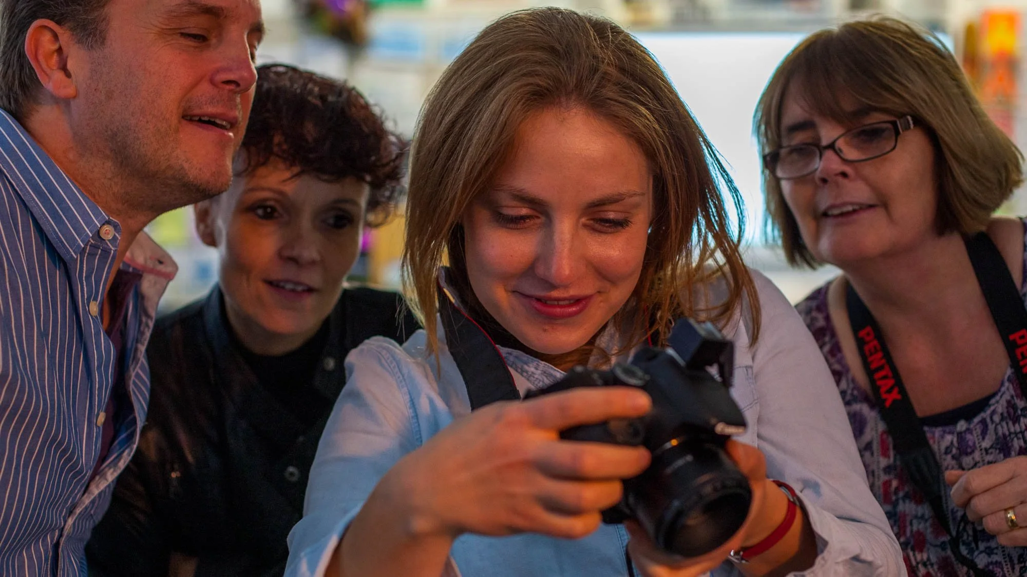 Photography students reviewing images and learning how camera settings work during a photography class.