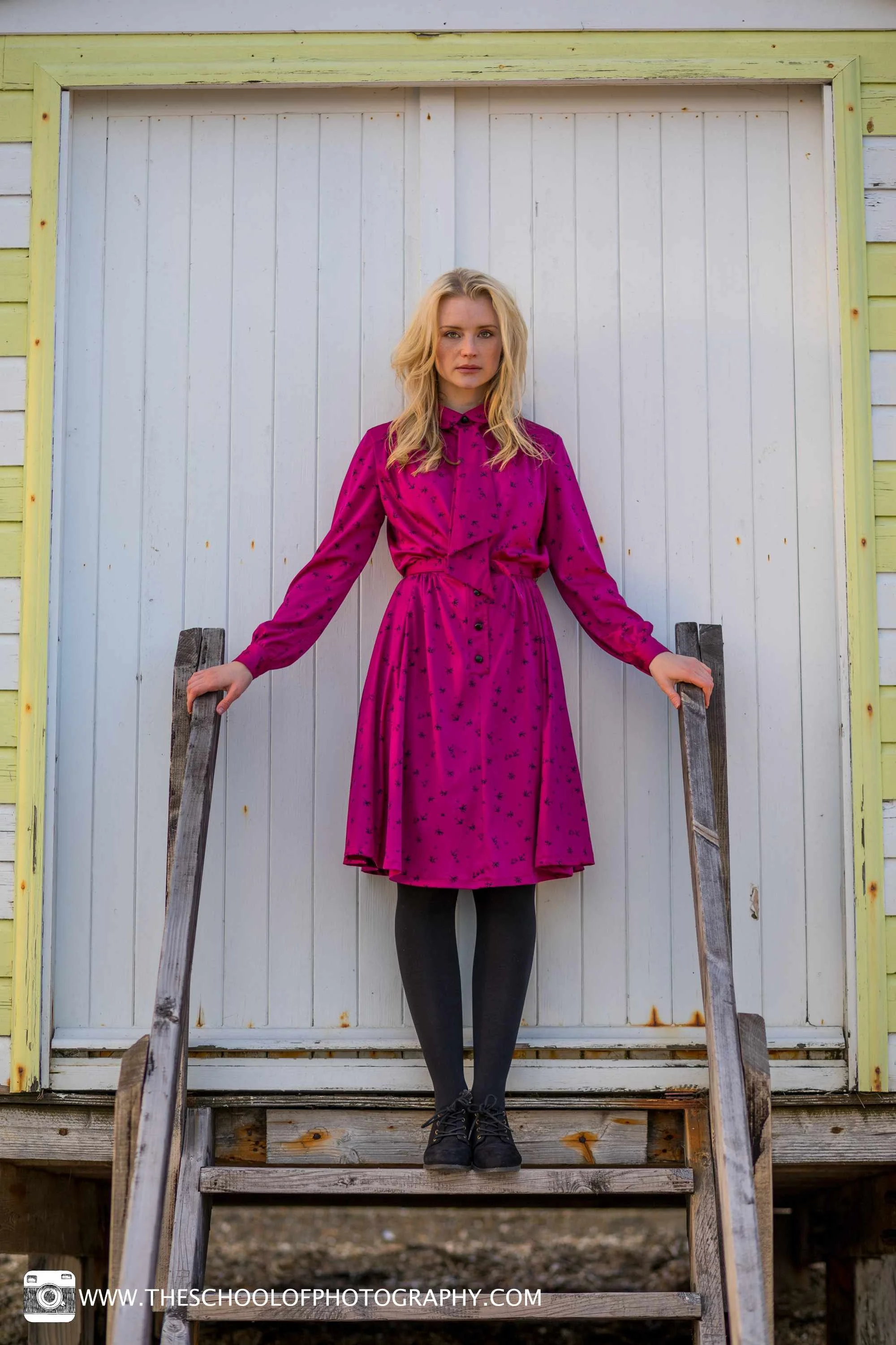 Symmetrical portrait photography composition with a woman centred in front of a beach hut