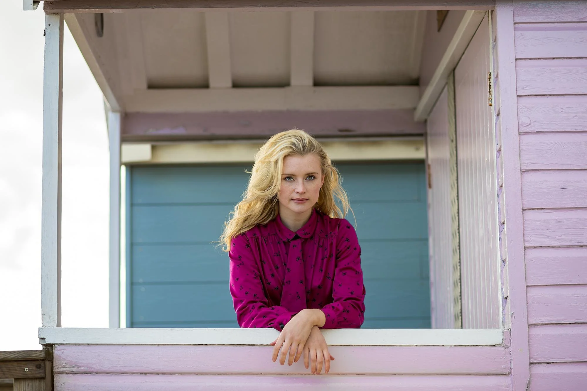 Portrait of a woman framed by a window opening demonstrating the framing composition technique in photography.