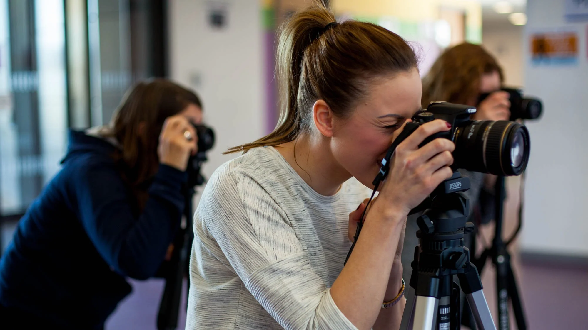 Students using DSLR cameras on tripods during a photography class.