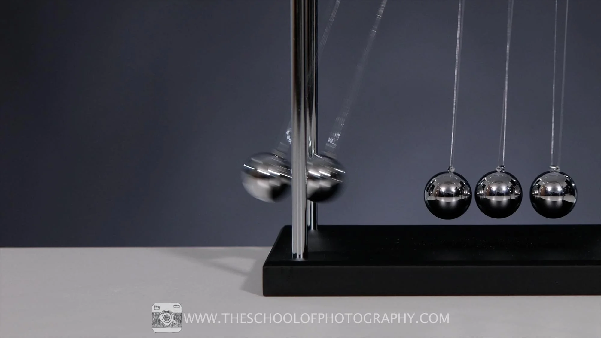 Newton’s cradle with metal balls in motion, demonstrating motion blur caused by slower shutter speed in photography.