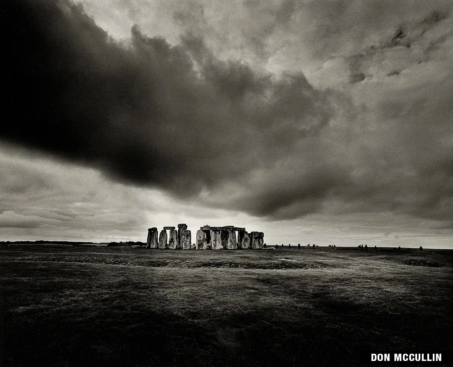 Black and white photograph of Stonehenge under a dramatic, cloudy sky by Don McCullin.