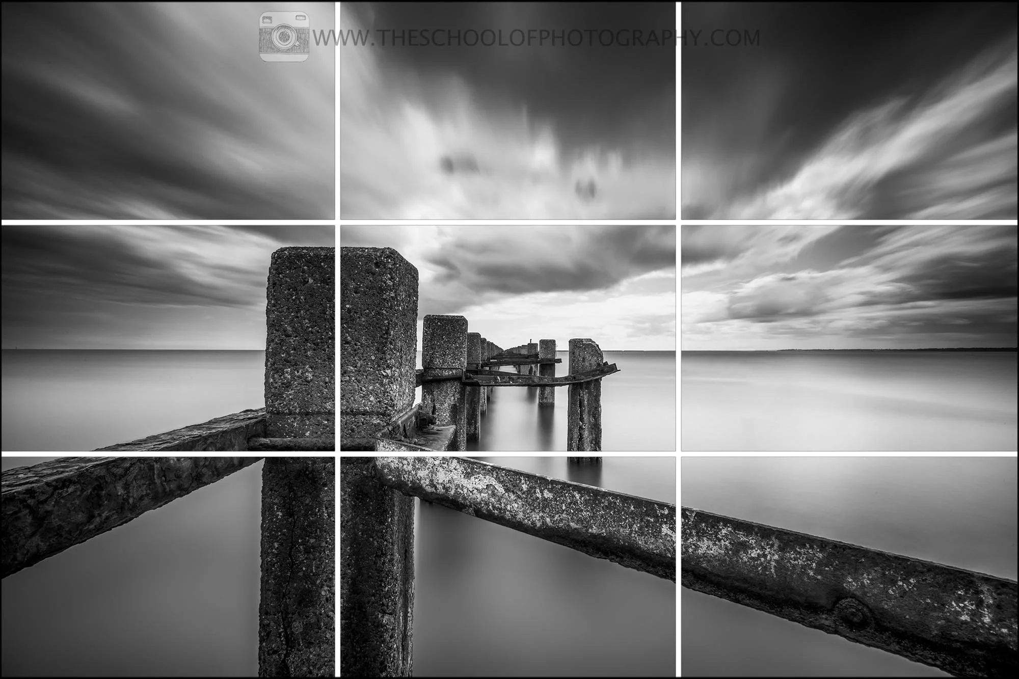 Black and white long exposure seascape with wooden posts leading into the water, overlaid with a rule of thirds grid to demonstrate composition.