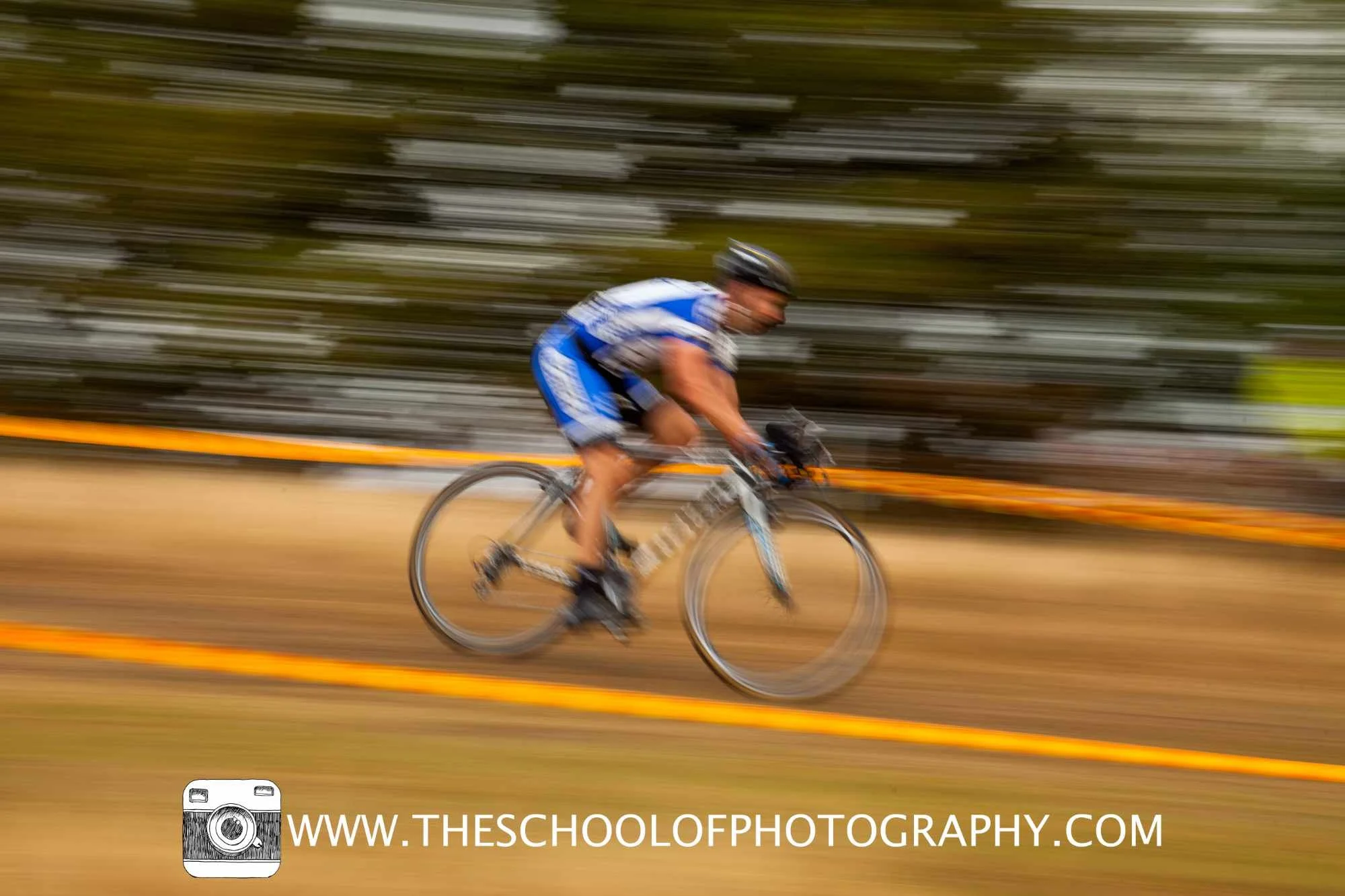 Cyclist in blue racing kit captured with a panning technique, creating strong horizontal motion blur in the background.