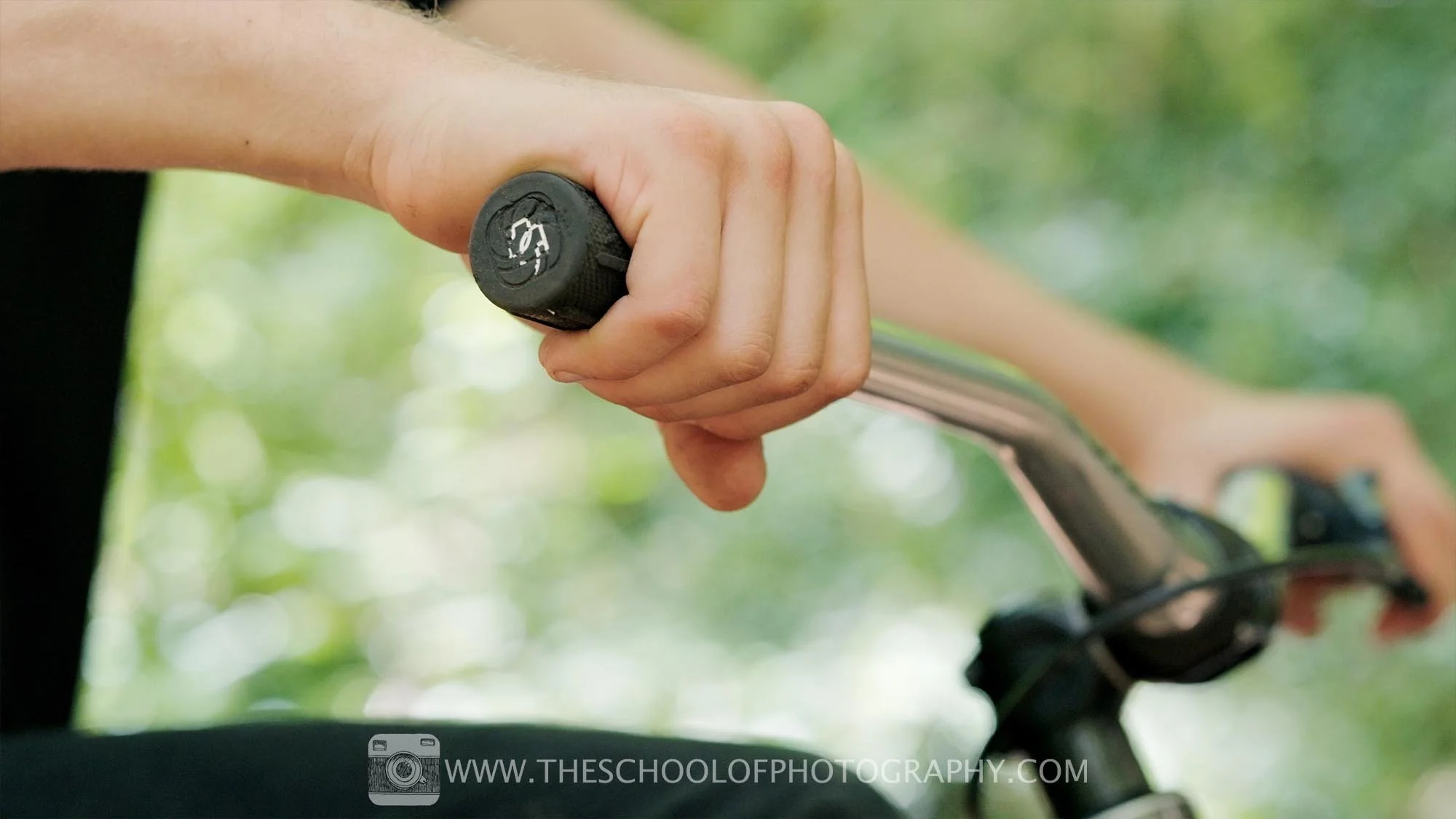 Close-up detail shot of a person’s hand gripping bicycle handlebars, with a blurred background to emphasise texture and focus.