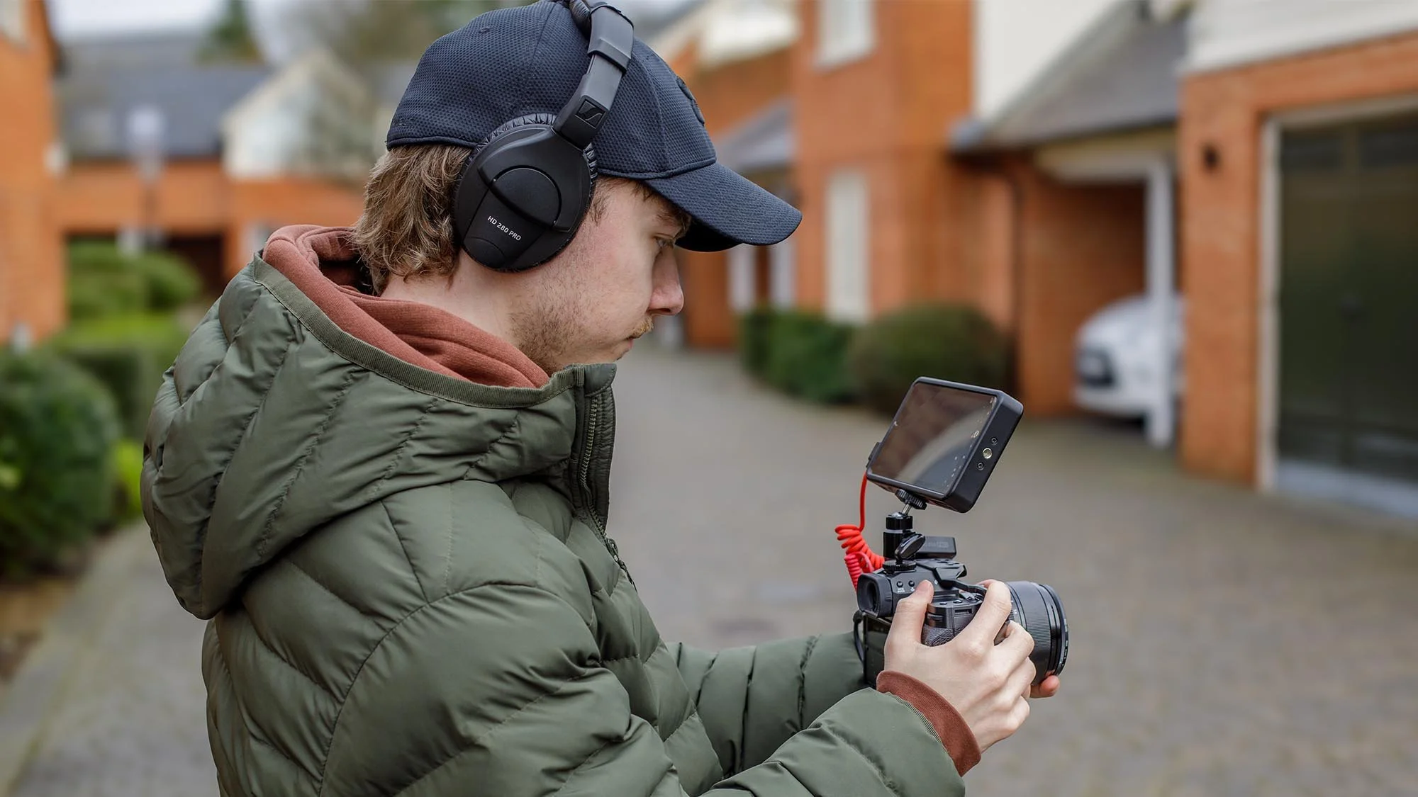 Student filming with a mirrorless camera and external monitor during an online videography course