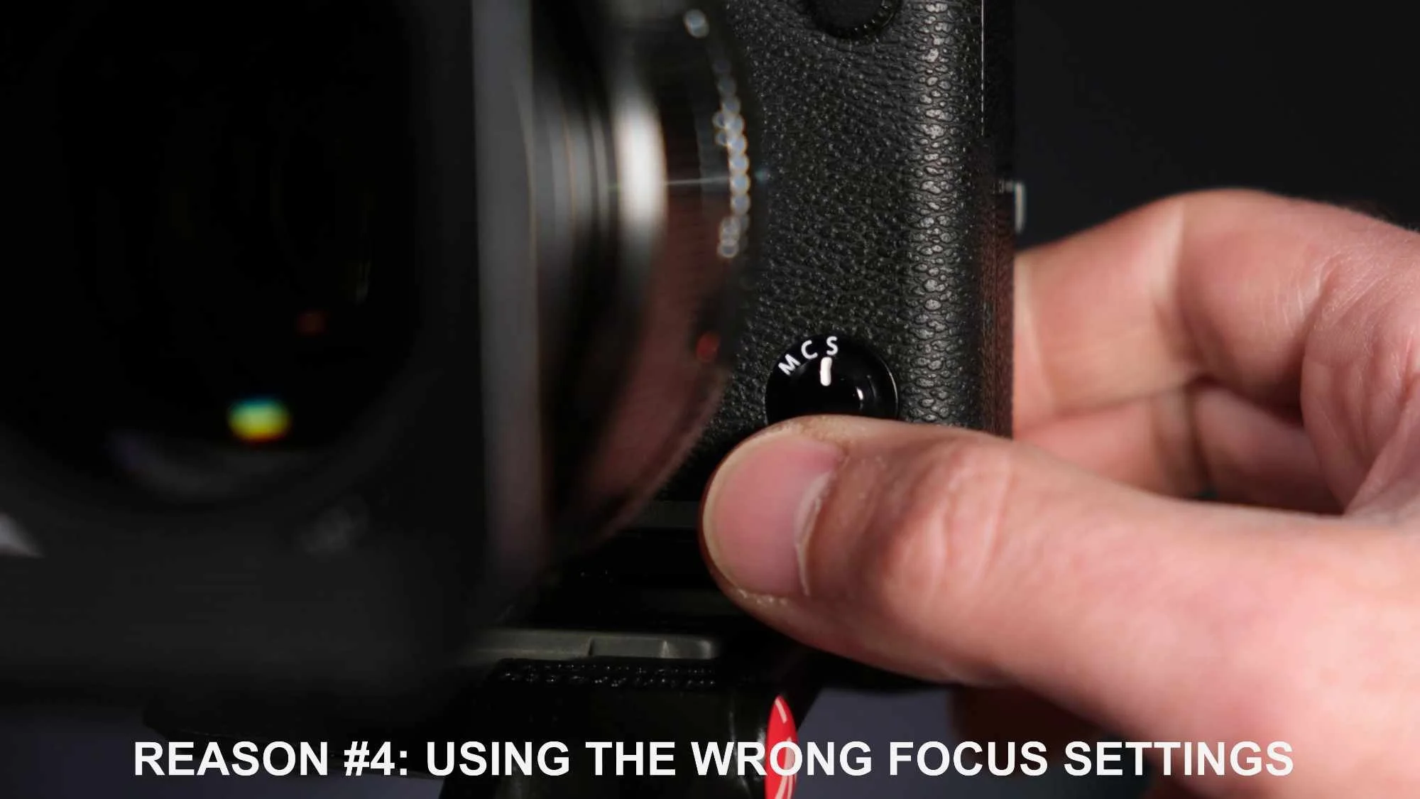 Close-up of a hand adjusting the M/C/S focus mode selector on a camera.