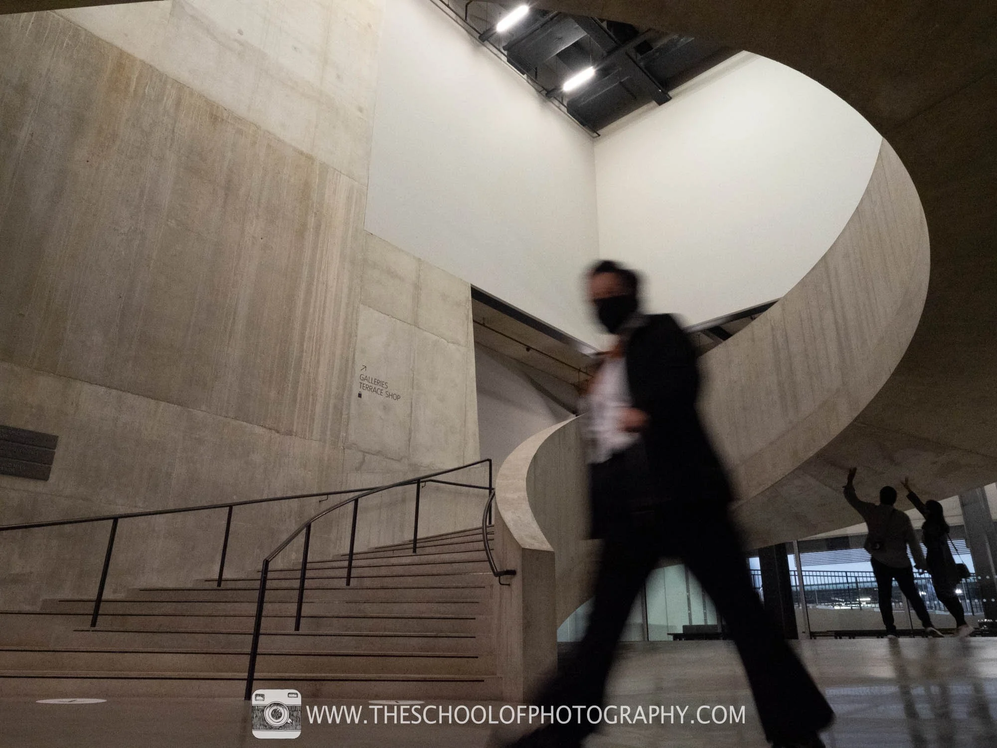 Before image: concrete interior with spiral stairs and people, some blurred by motion.