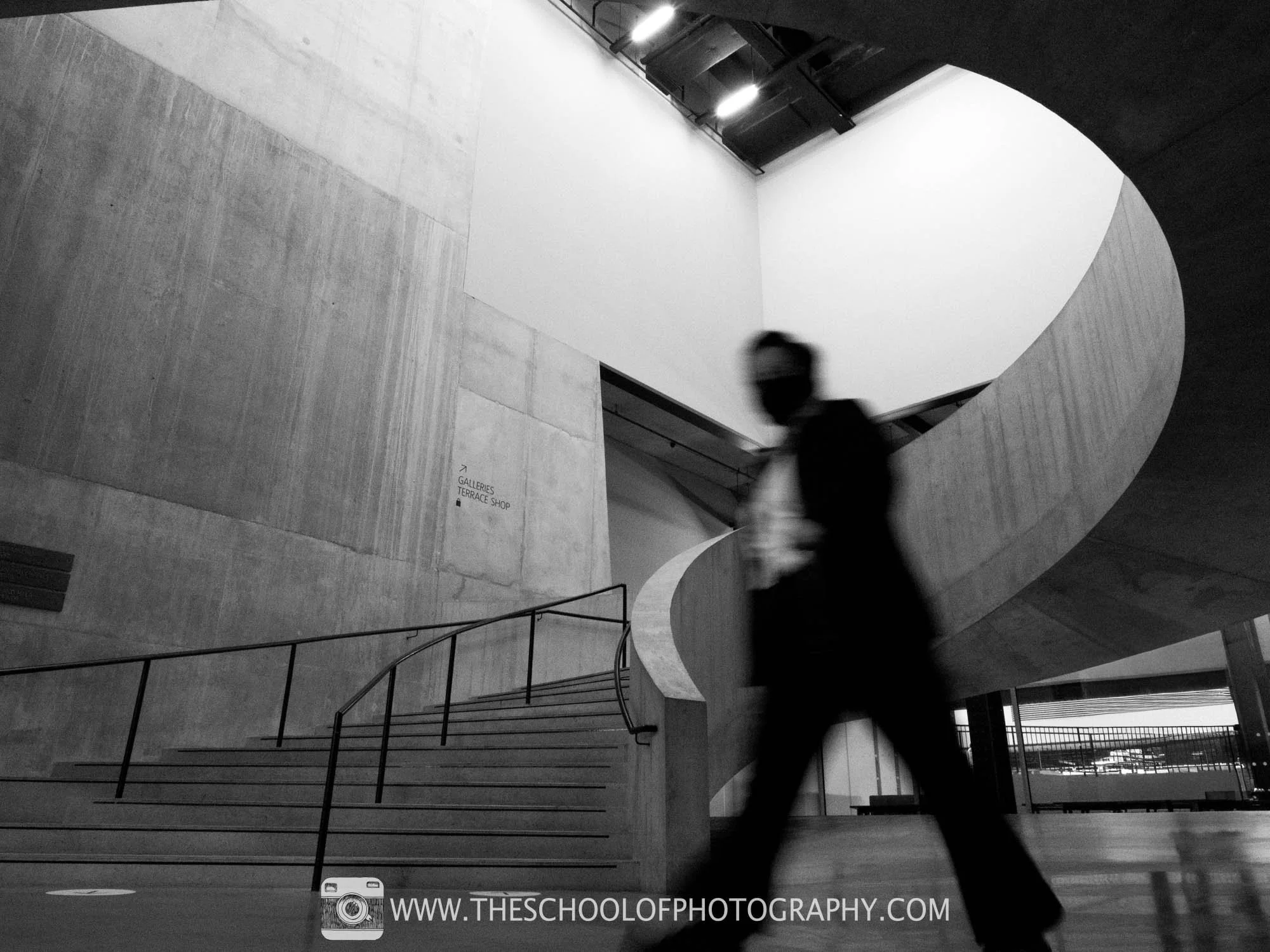 Final image: empty concrete interior with spiral stairs; one blurred person remains.