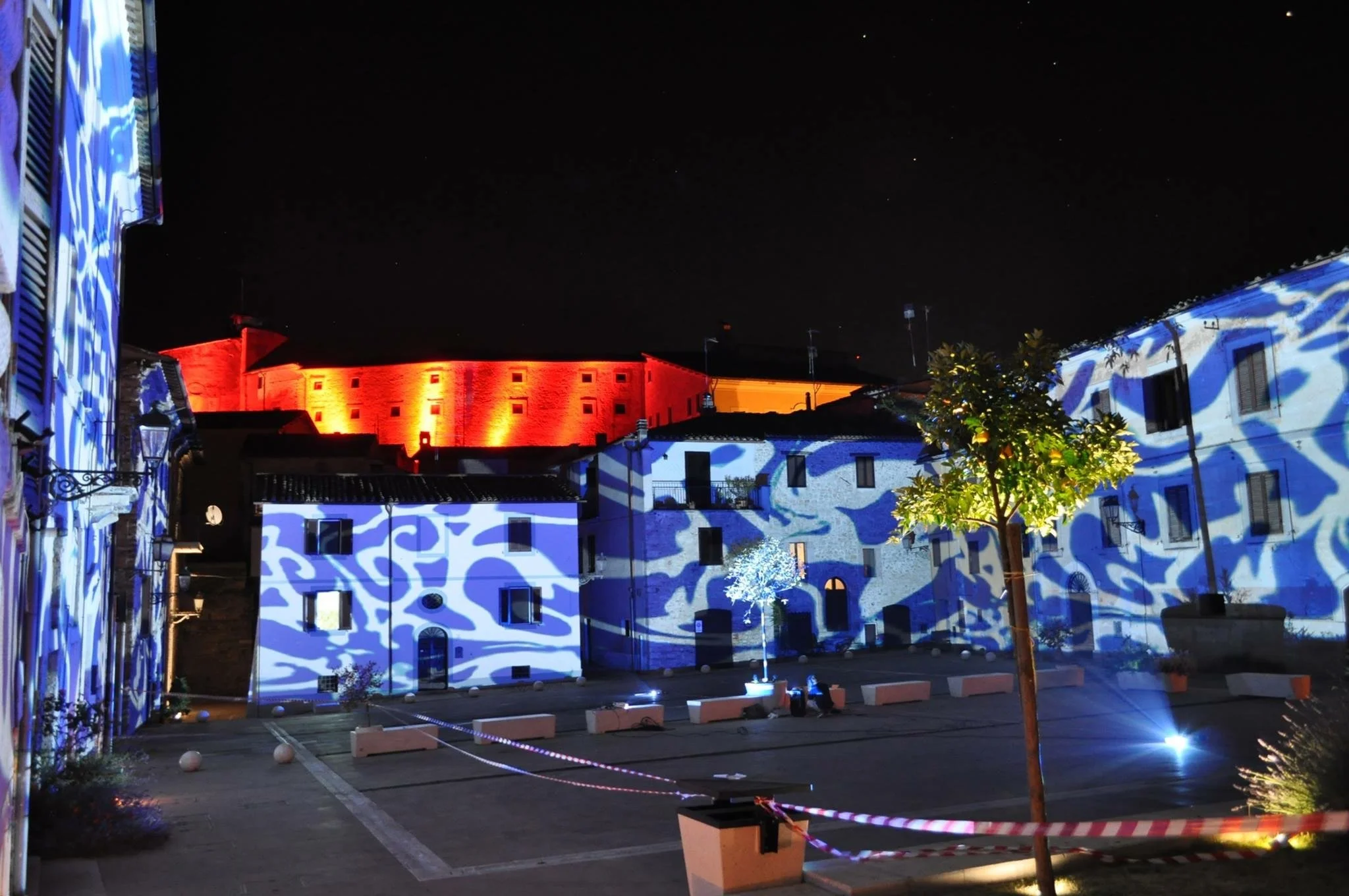 Diffuso luci colorate su edifici e castello in lontananza durante la notte.