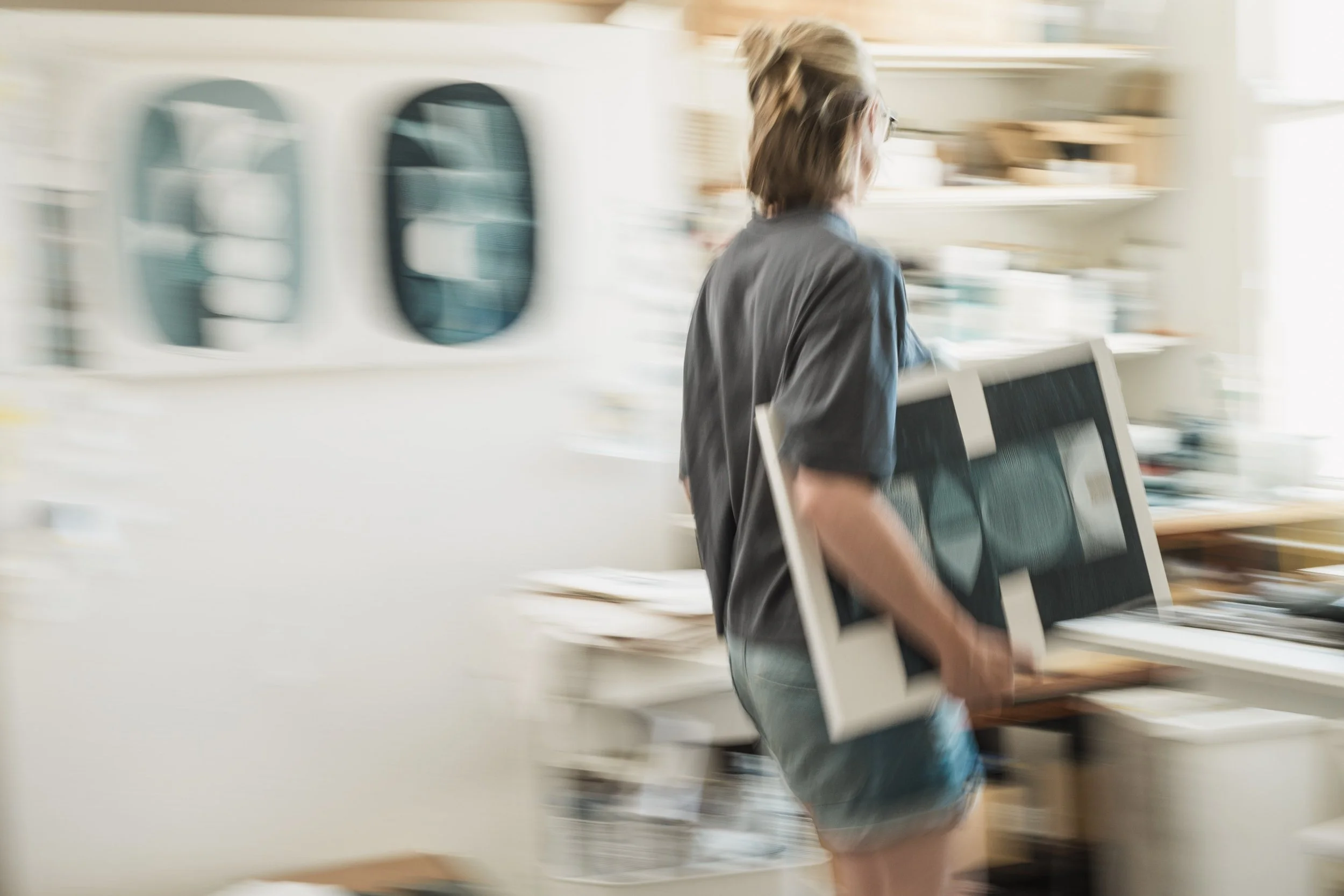 Blurred image of Sanna Annukka carrying a painting in her studio