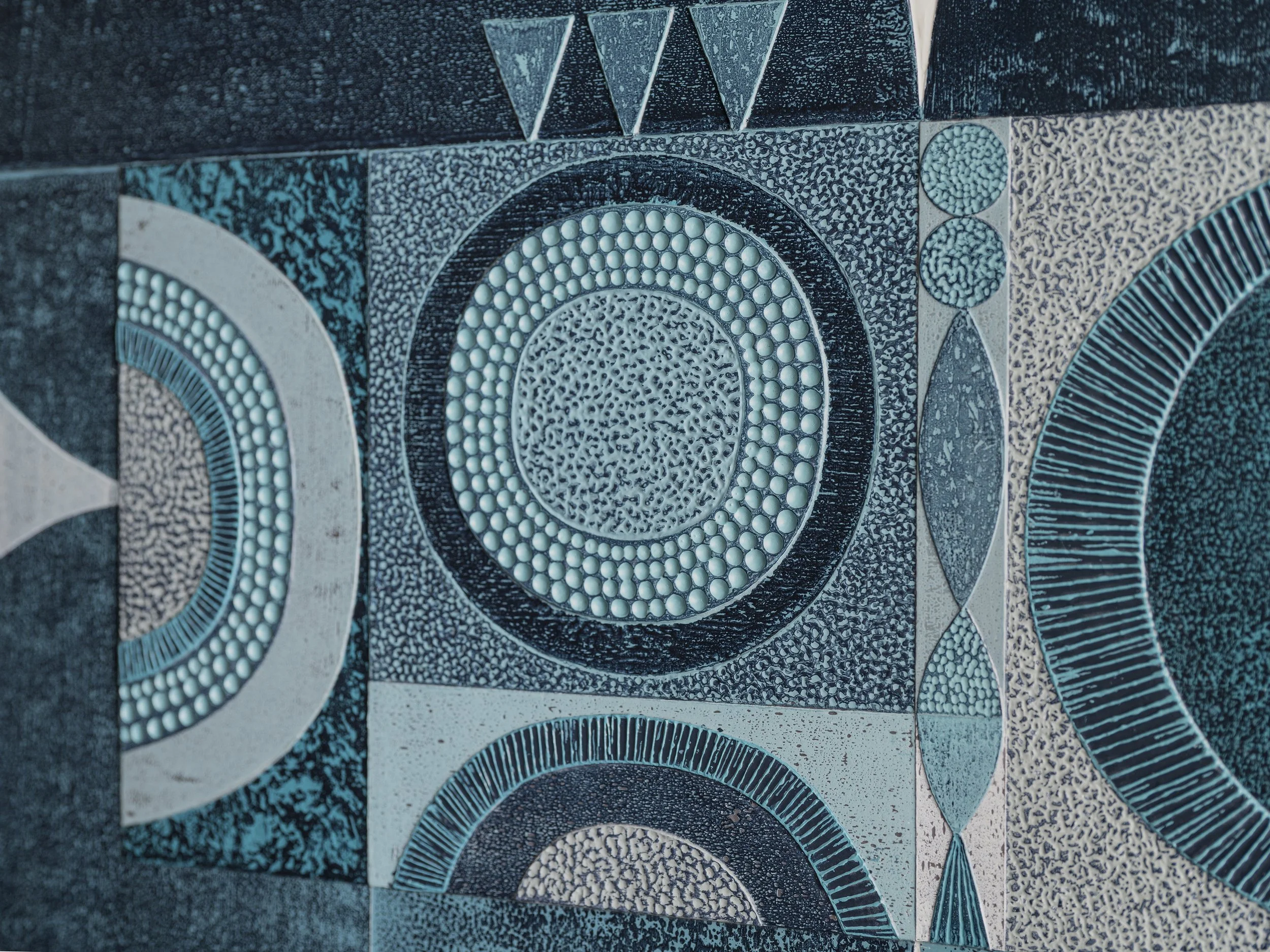 Close-up of a mosaic tile artwork featuring circular and geometric patterns in shades of blue, black, and white.