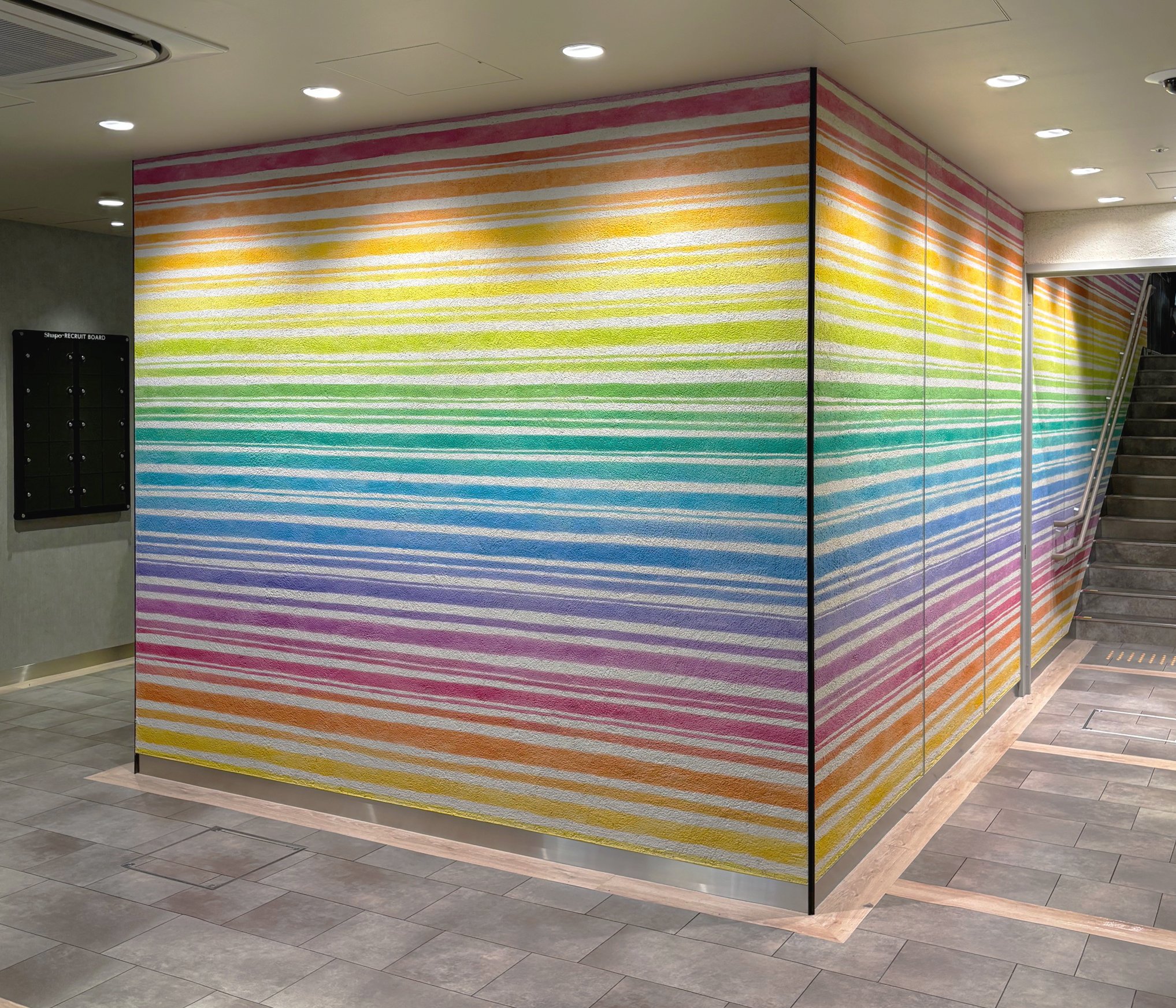 Shapo 小岩 ショッピング施設内公共アート 施主:(株)ジェイアール東日本都市開発 花火、川の水、渡る風、虹色の地層、この施設アートには土地に宿るエネルギーを虹色で表現した。壁面に虹色をたくさん染み込ませ、人々の喜びや笑顔を願った。多様性の街にはこの色がよく似合う。