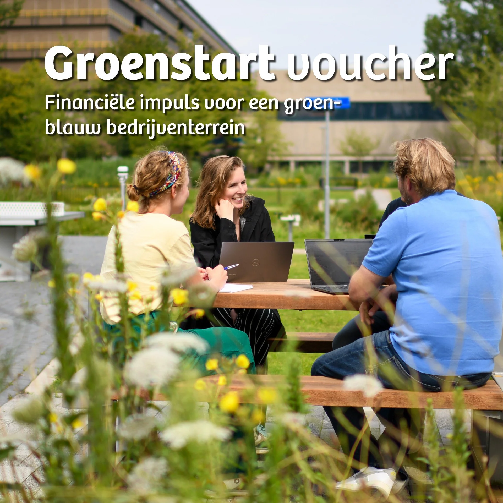 Mensen die in een tuin zitten en praten, met laptops op tafel, omringd door bloemen en bomen.