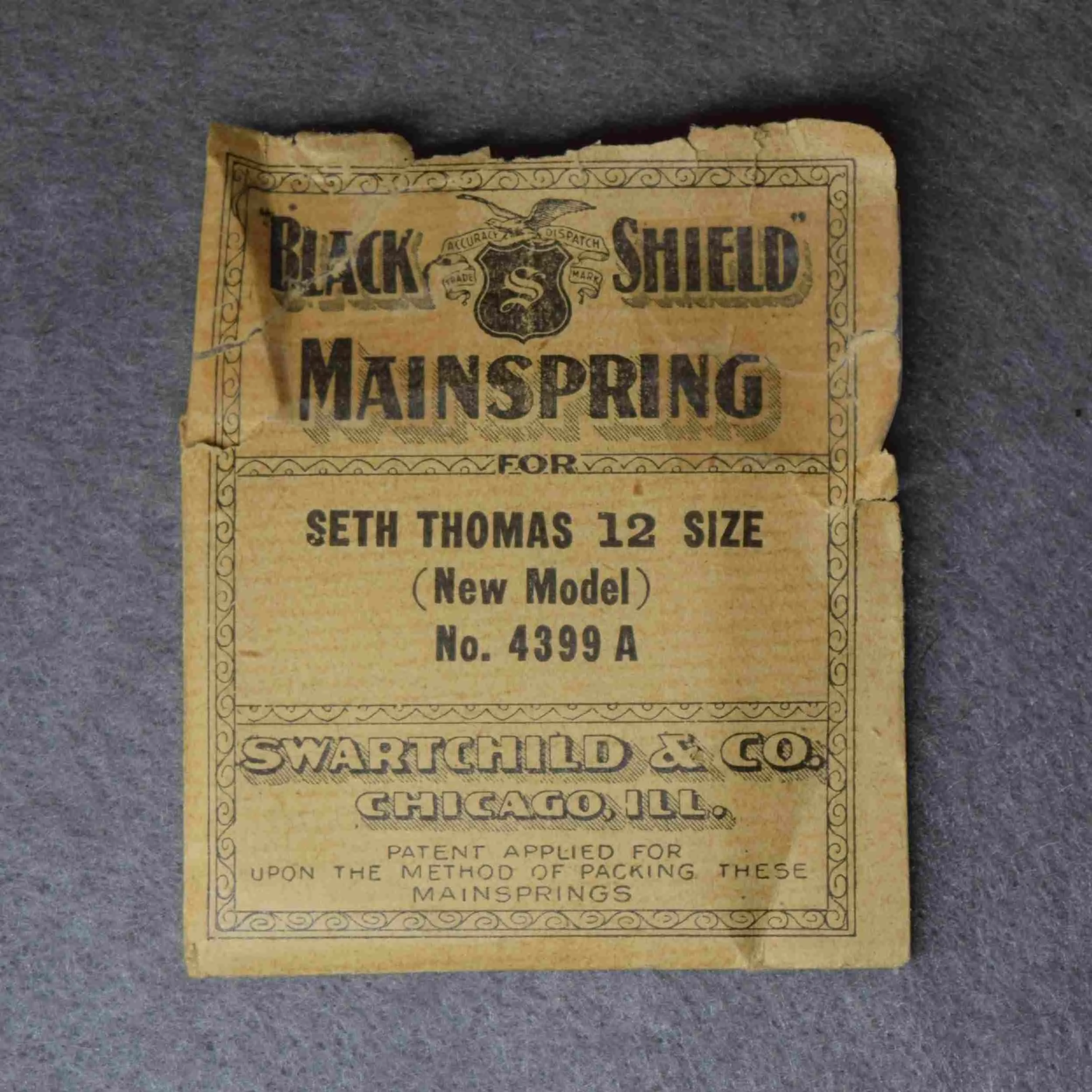 Black Shield Mainspring Alternate Package No. 4397 – Seth Thomas 18-size No. 536 (spring in waxed paper is not retained by a clamp)
