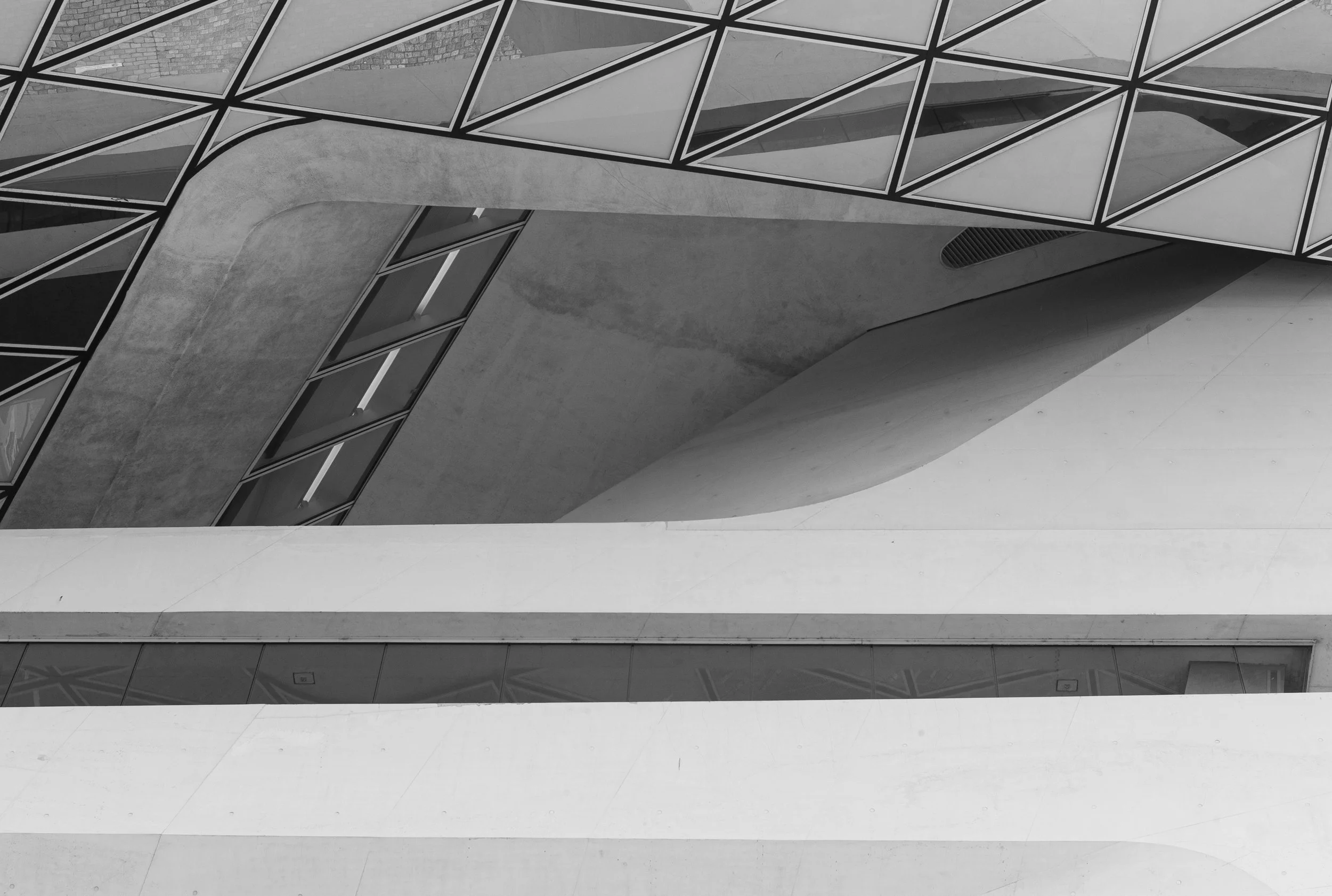 Close-up of a modern architectural building with geometric windows and curved concrete structures in black and white.