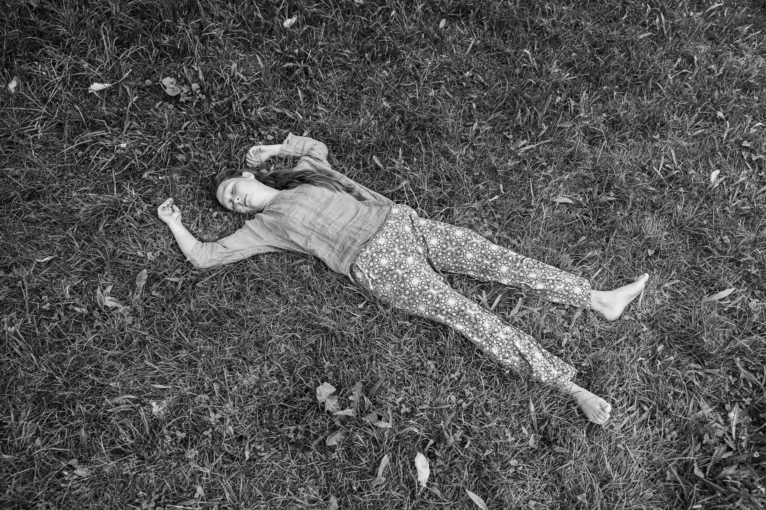 Ein junges Mädchen liegt schlafend auf dem Gras im Freien.