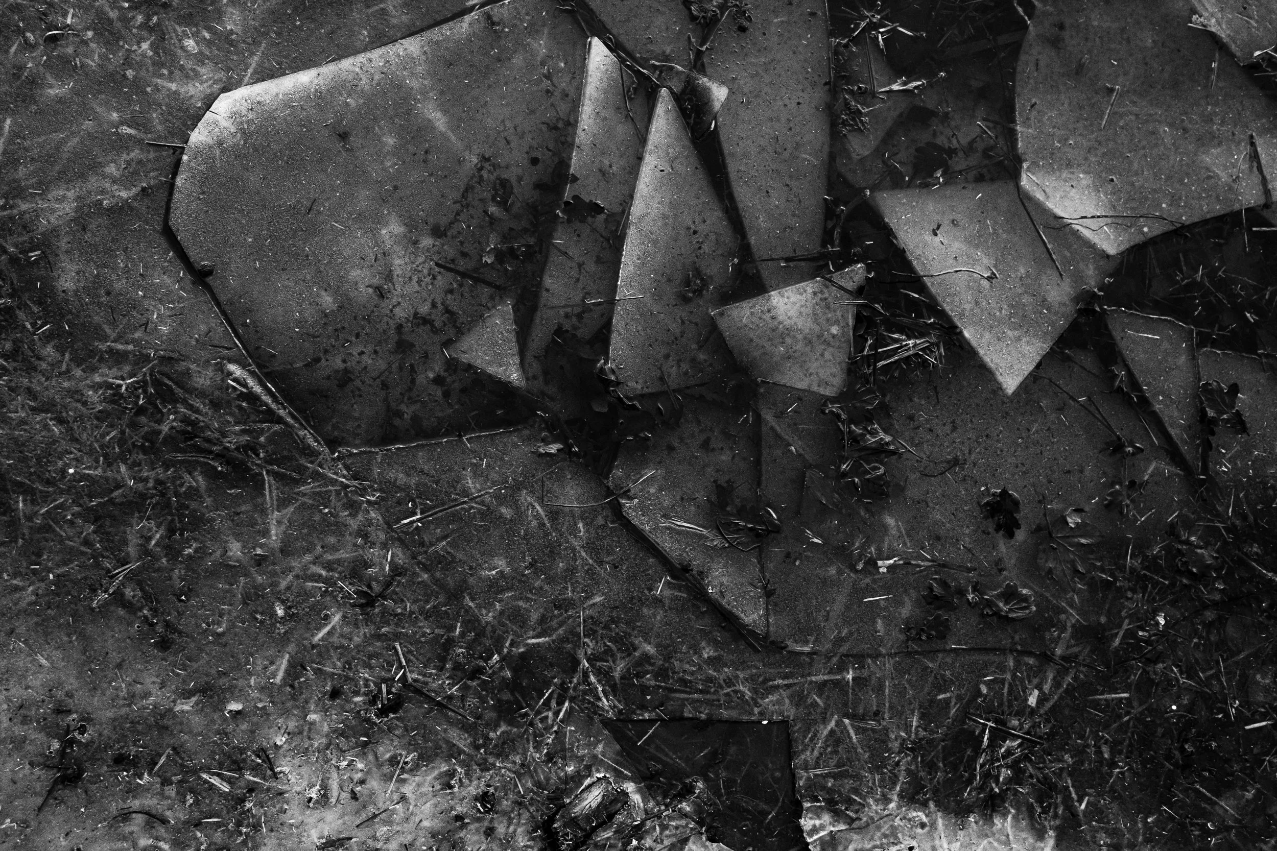 Zerstörte Fenster mit Glasscherben auf staubigem Boden