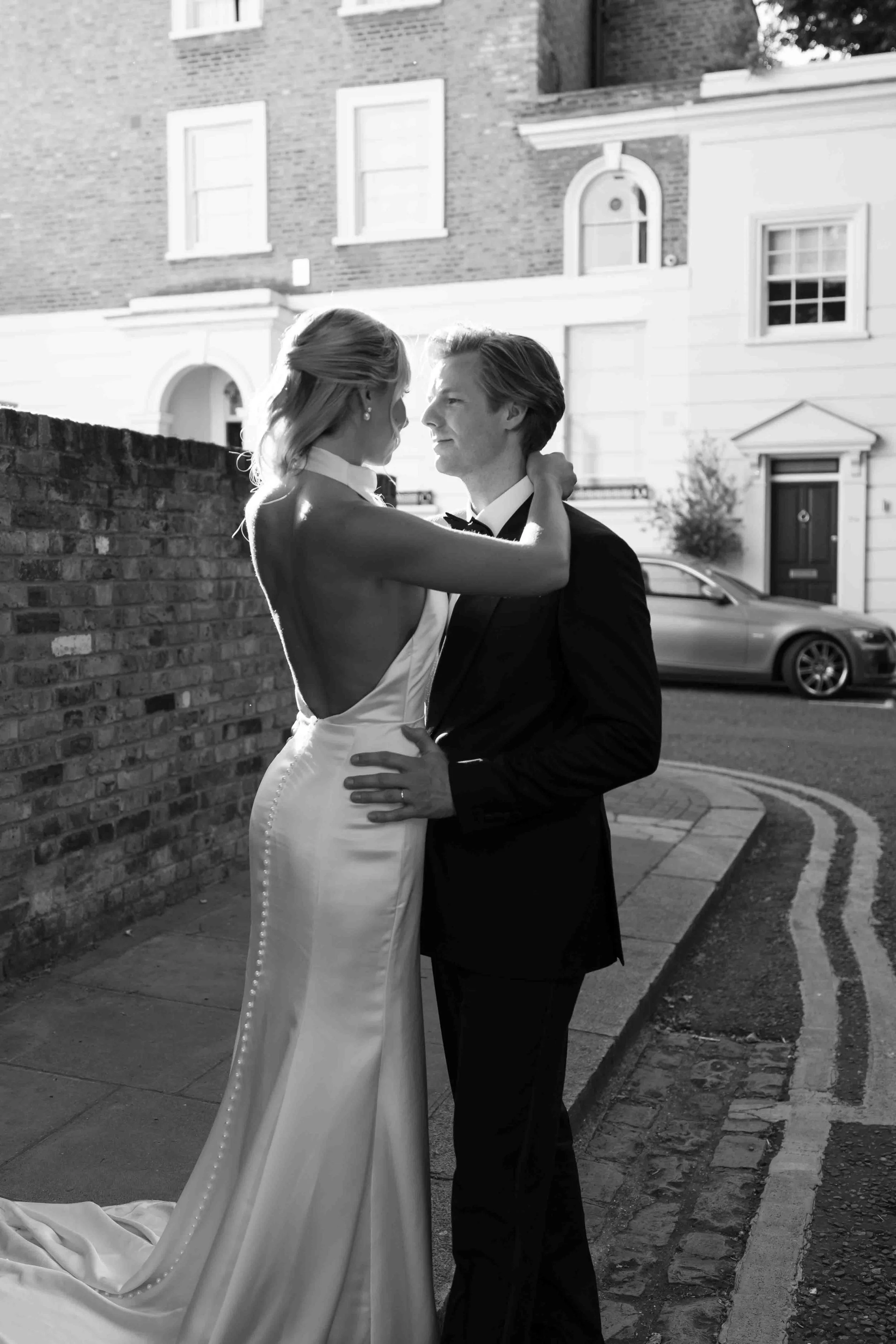 editorial black and white photo of a bride and groom embracing intimatley on a quiet street in Chelsea London