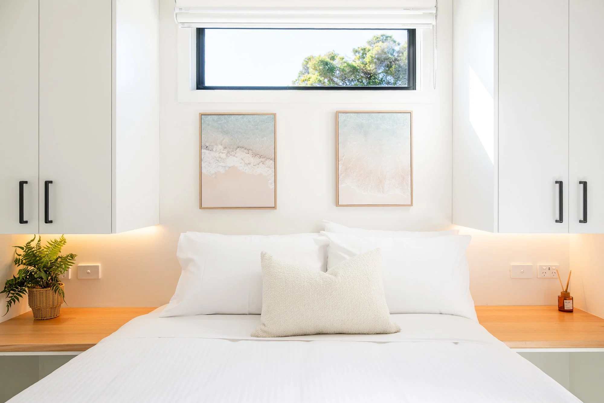 Photography capturing bright modern holiday accommodation bedroom with timber bedside cabinetry in Victoria, Australia