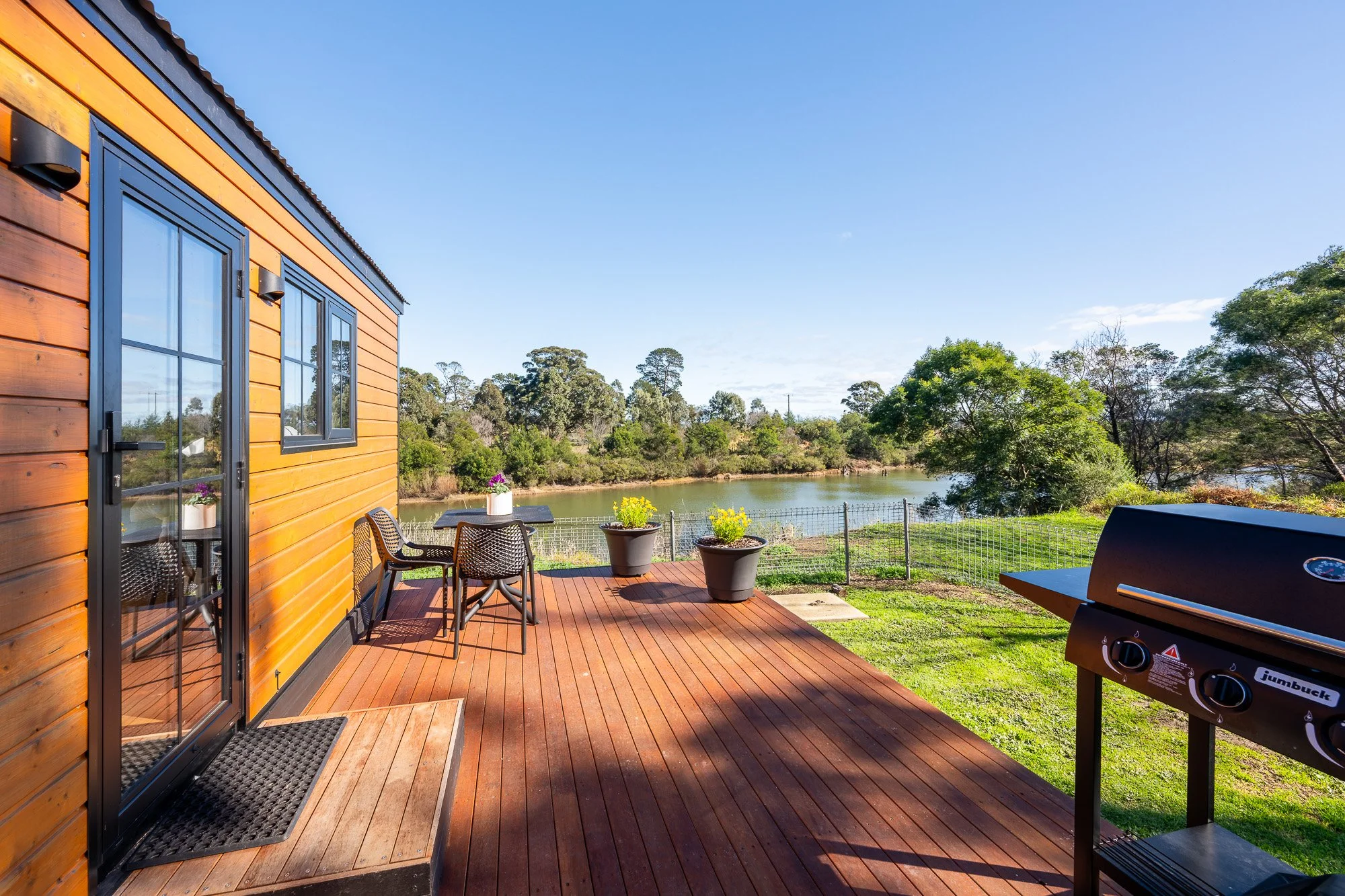 Holiday park cabin deck overlooking landscaped grounds and the Avon River in Gippsland