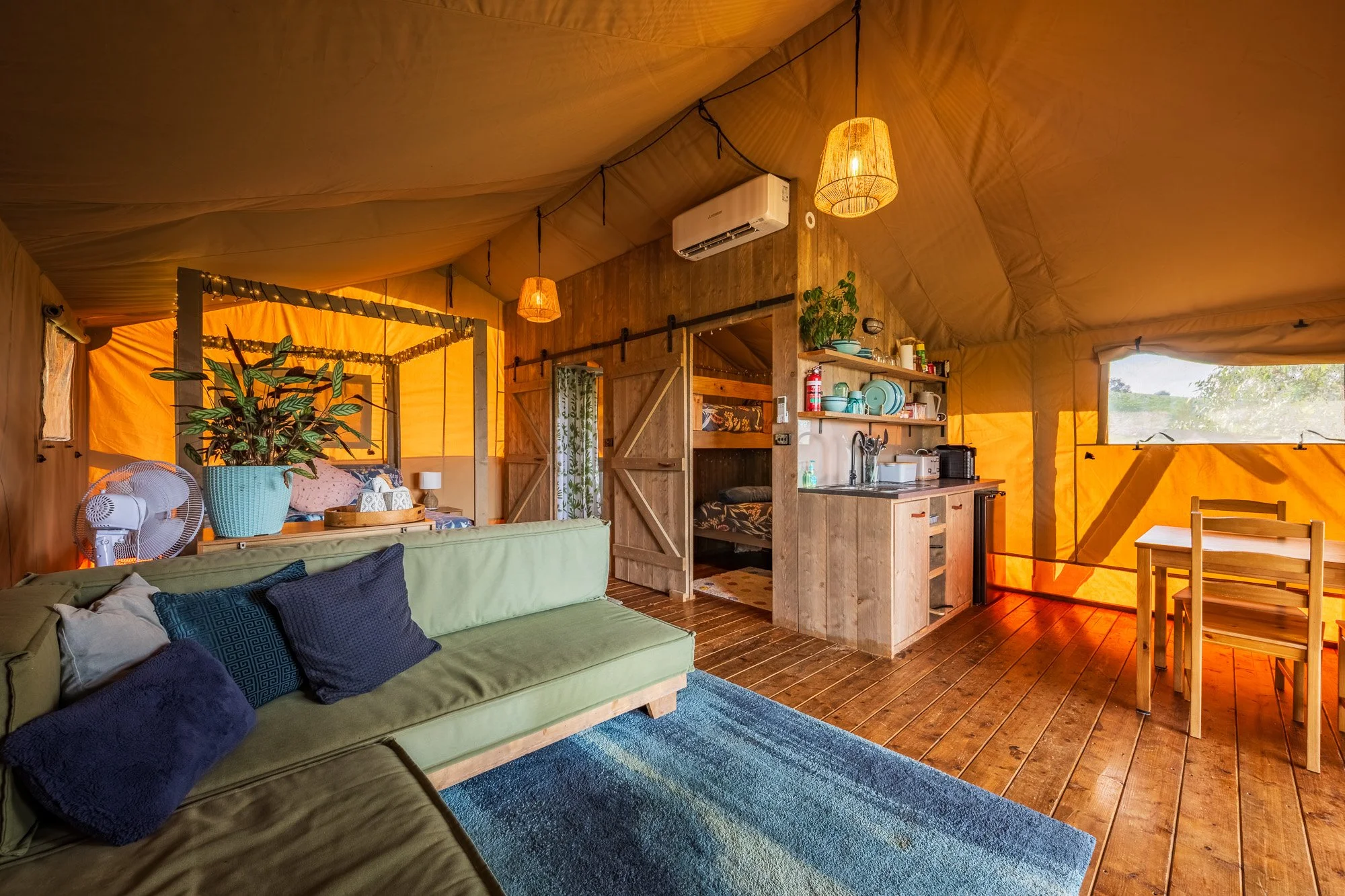 Media inside luxury glamping tent interior with lounge, kitchen and dining area