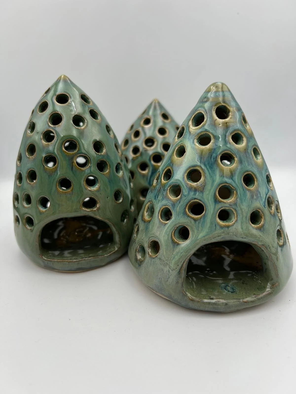 Drie keramische decoratieve vuurscheppen met gekleurde glazuur en perforaties.