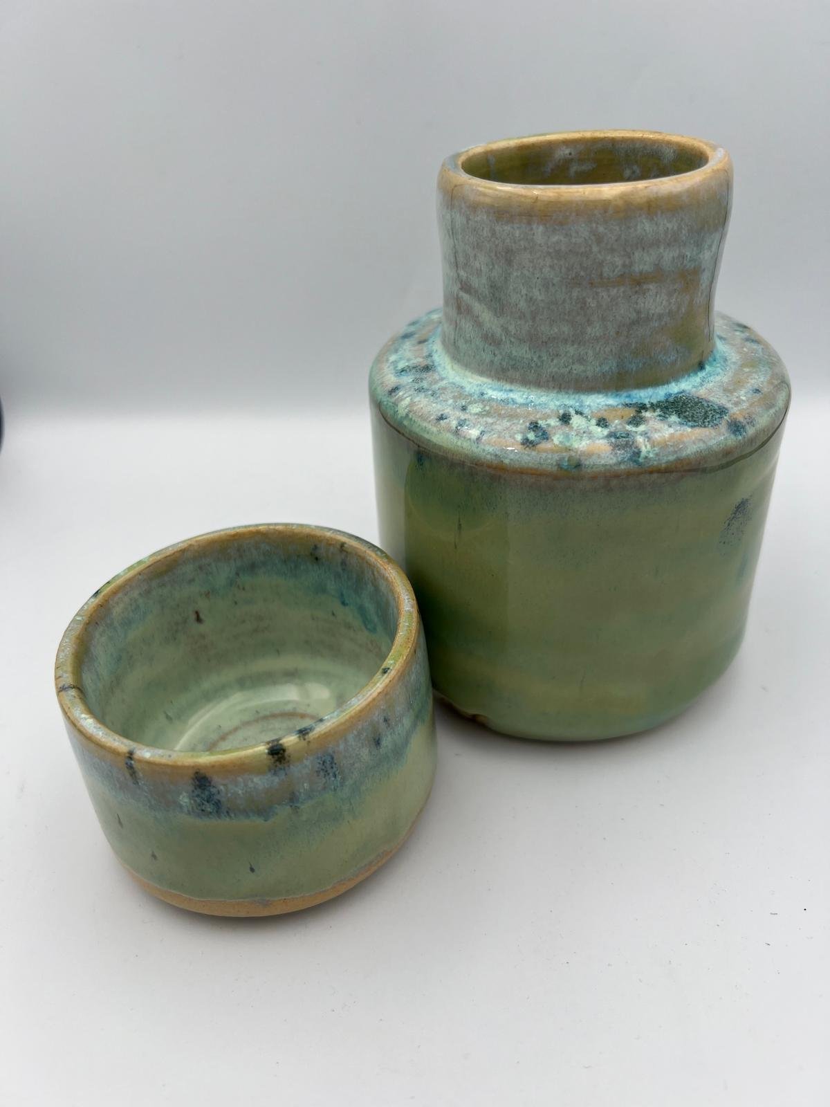 Twee groene gekleurde keramische vazen, één groot met een opening op de bovenkant en één klein, beide met een glanzende afwerking.