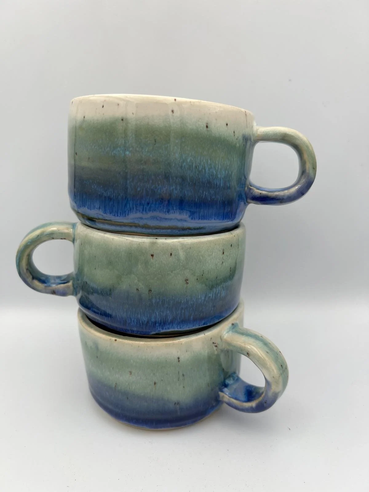 Drie gestapelde keramieken koffie- of thee cups met blauwe, groene en witte glazuur