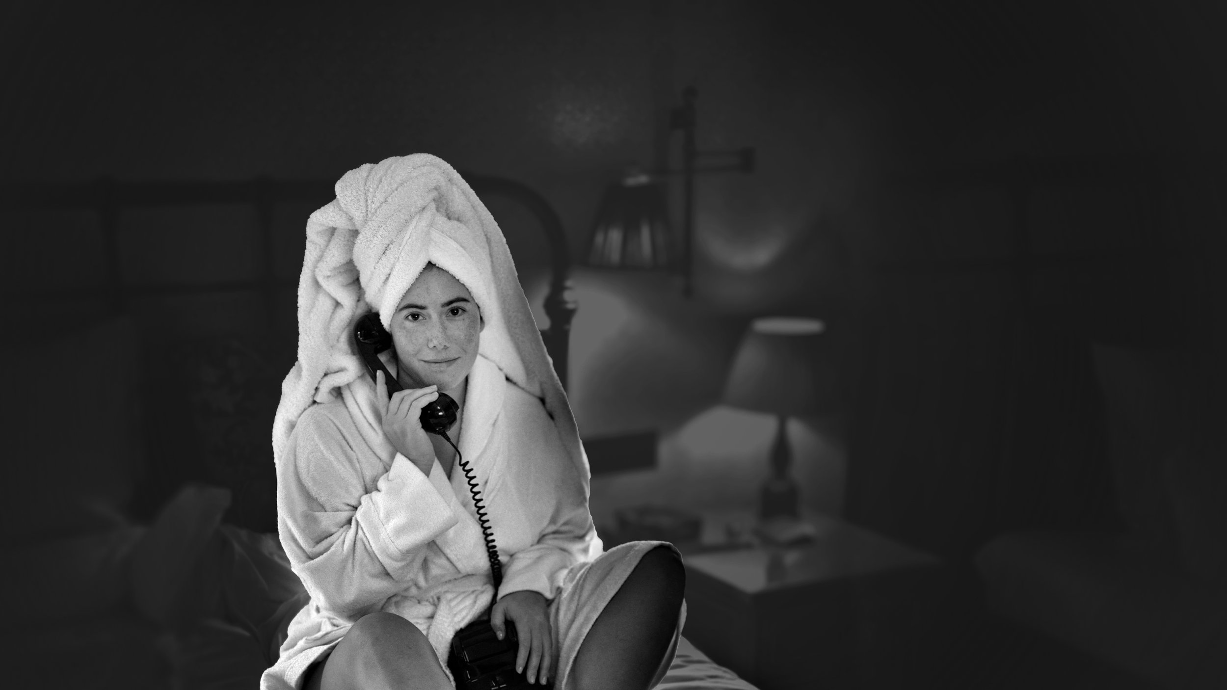Simona Deifta speaking on a rotary telephone in a white robe and towel