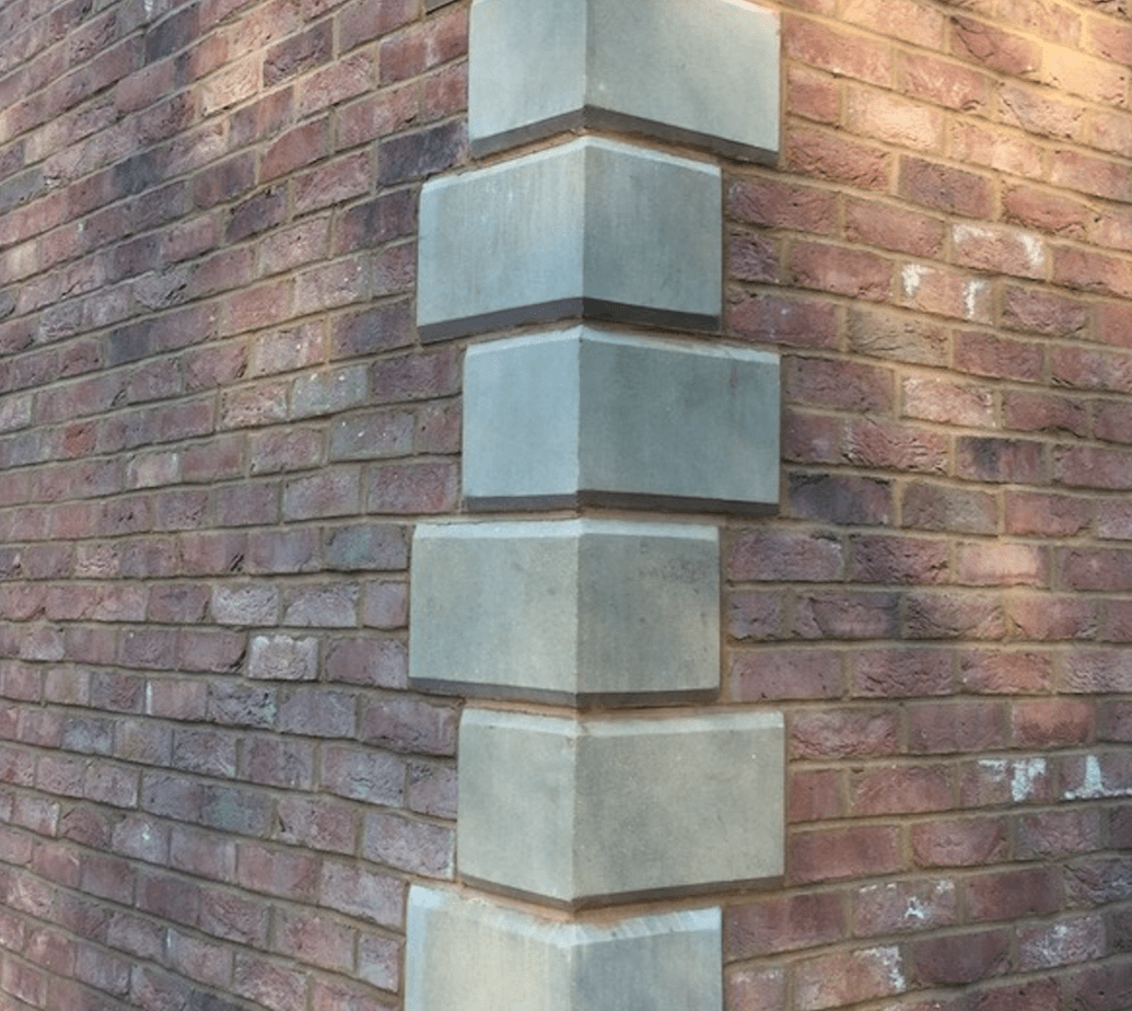 Close-up of a brick building corner with concrete blocks at the edge.