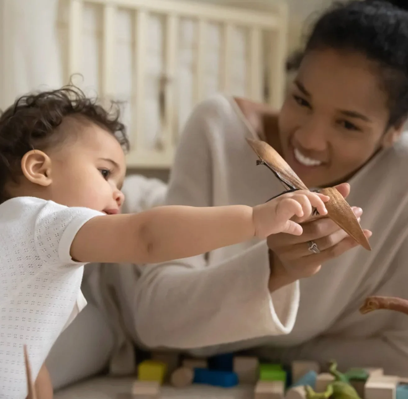 A woman and a young child playing with a wooden bird puppet.