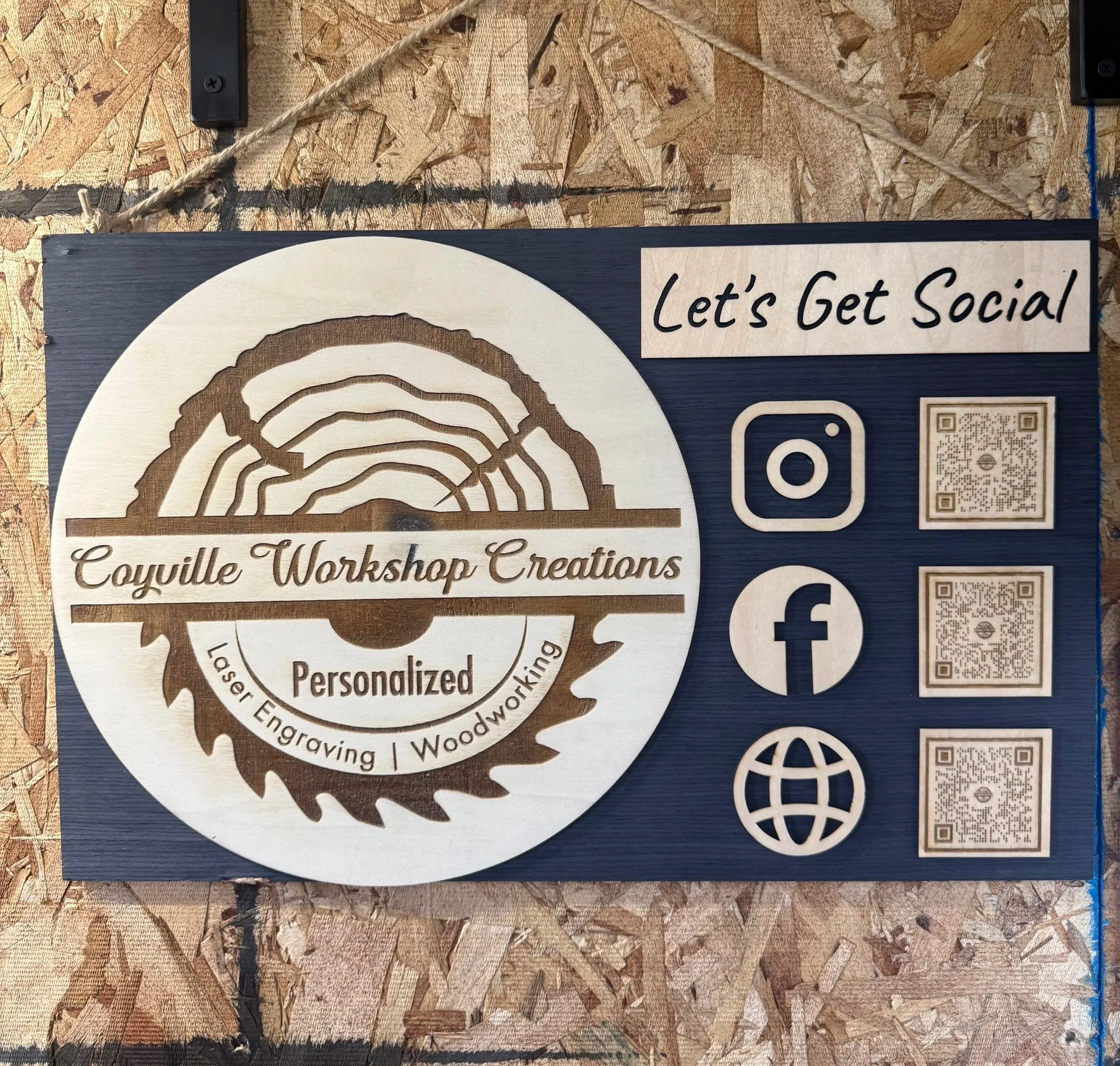 Wooden sign with the words 'Let's Get Social' on it and social media icons, placed on a wood surface with a string of yarn above it.