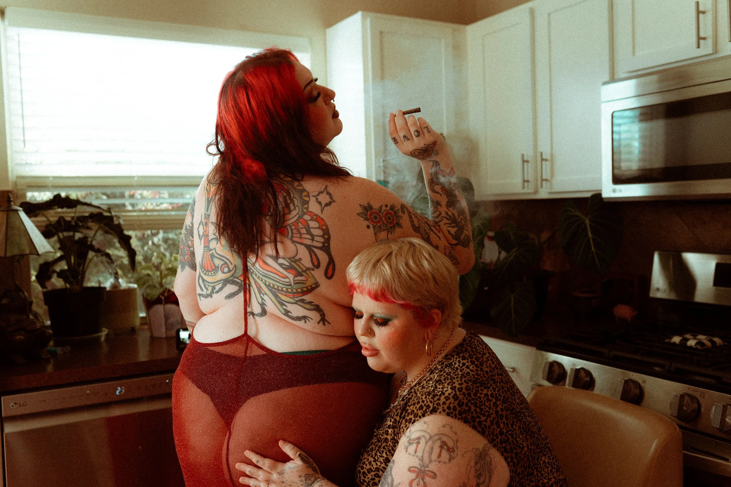 Austin, Texas plus size lesbian couple, one red hair with tattoos and one blonde with colorful makeup embracing