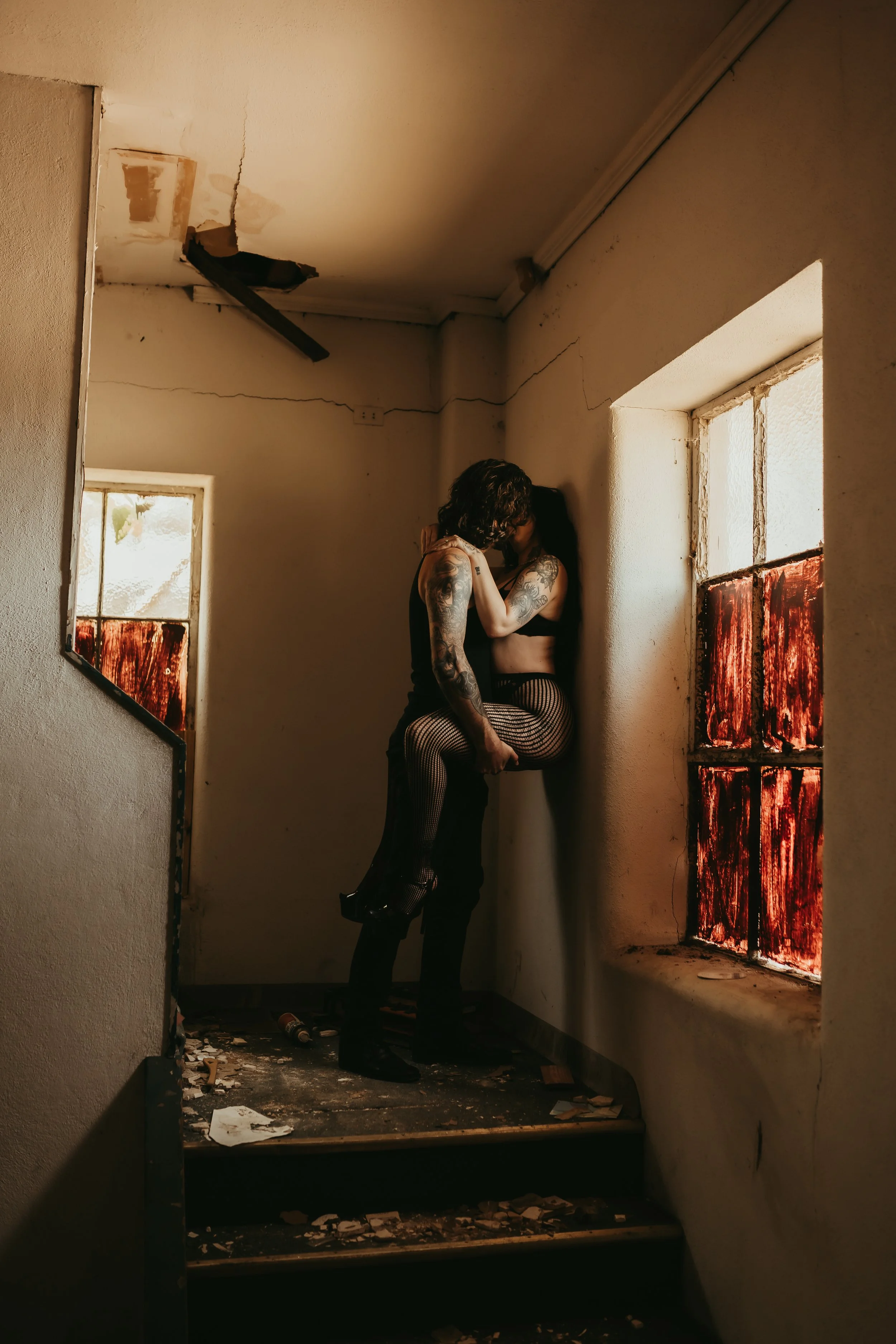 A couple in an abandoned building in lingerie. the man has the woman pressed against the wall embracing in a passionate kiss. abandoned building in Houston Texas