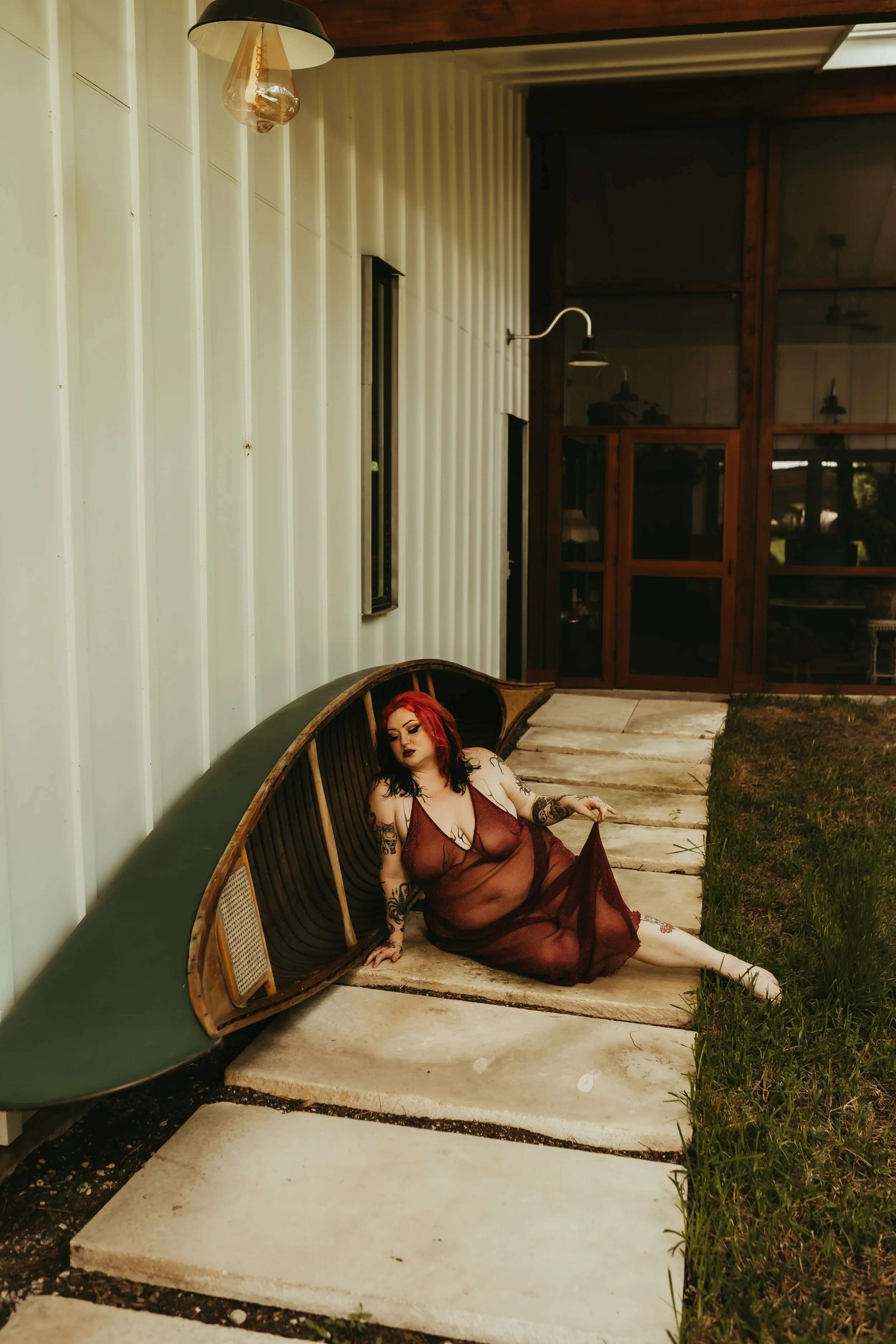 red head white woman in a sheer red dress next to a green boat boudoir in Austin, texas