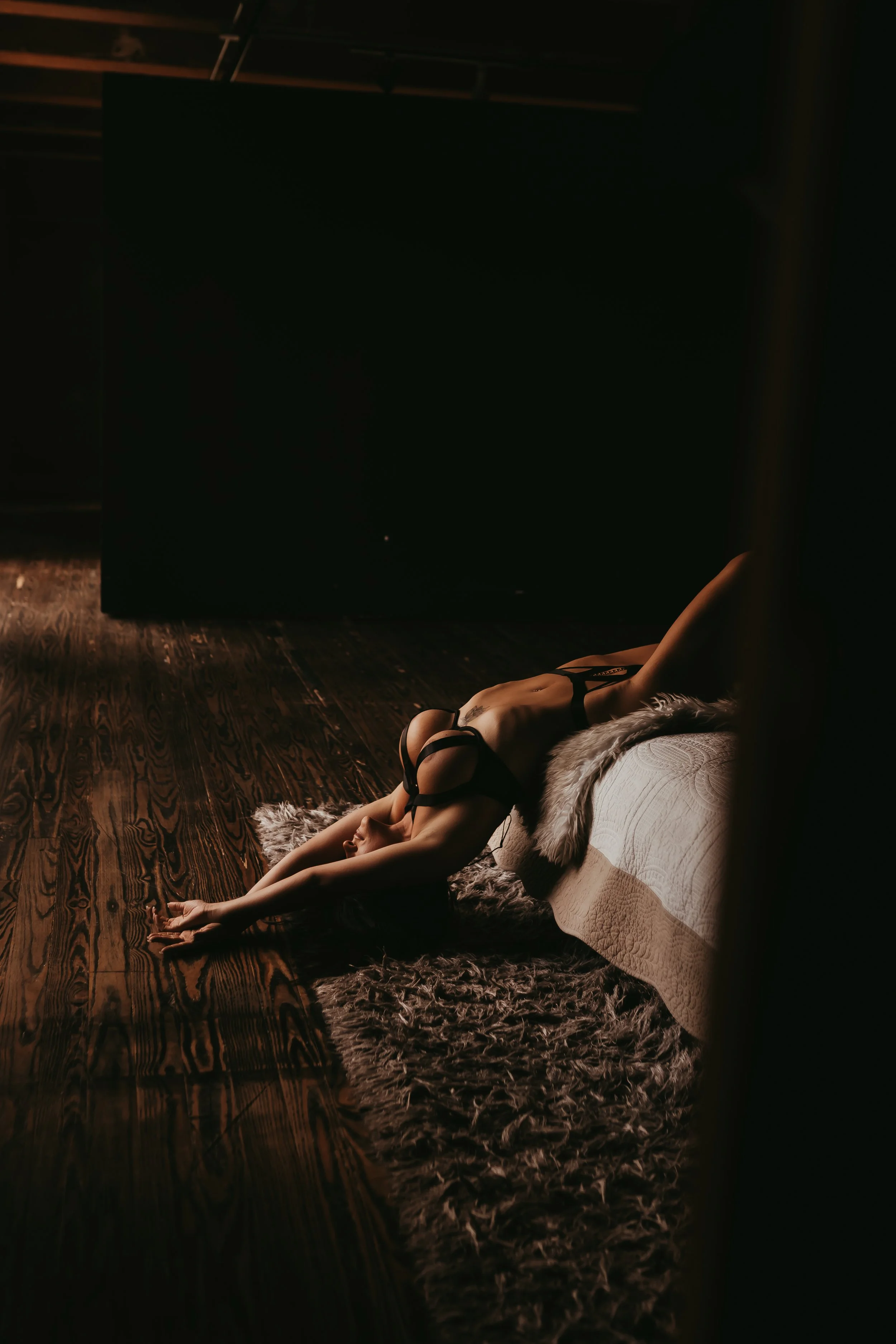 A tan woman wearing strappy lingerie in a bedroom