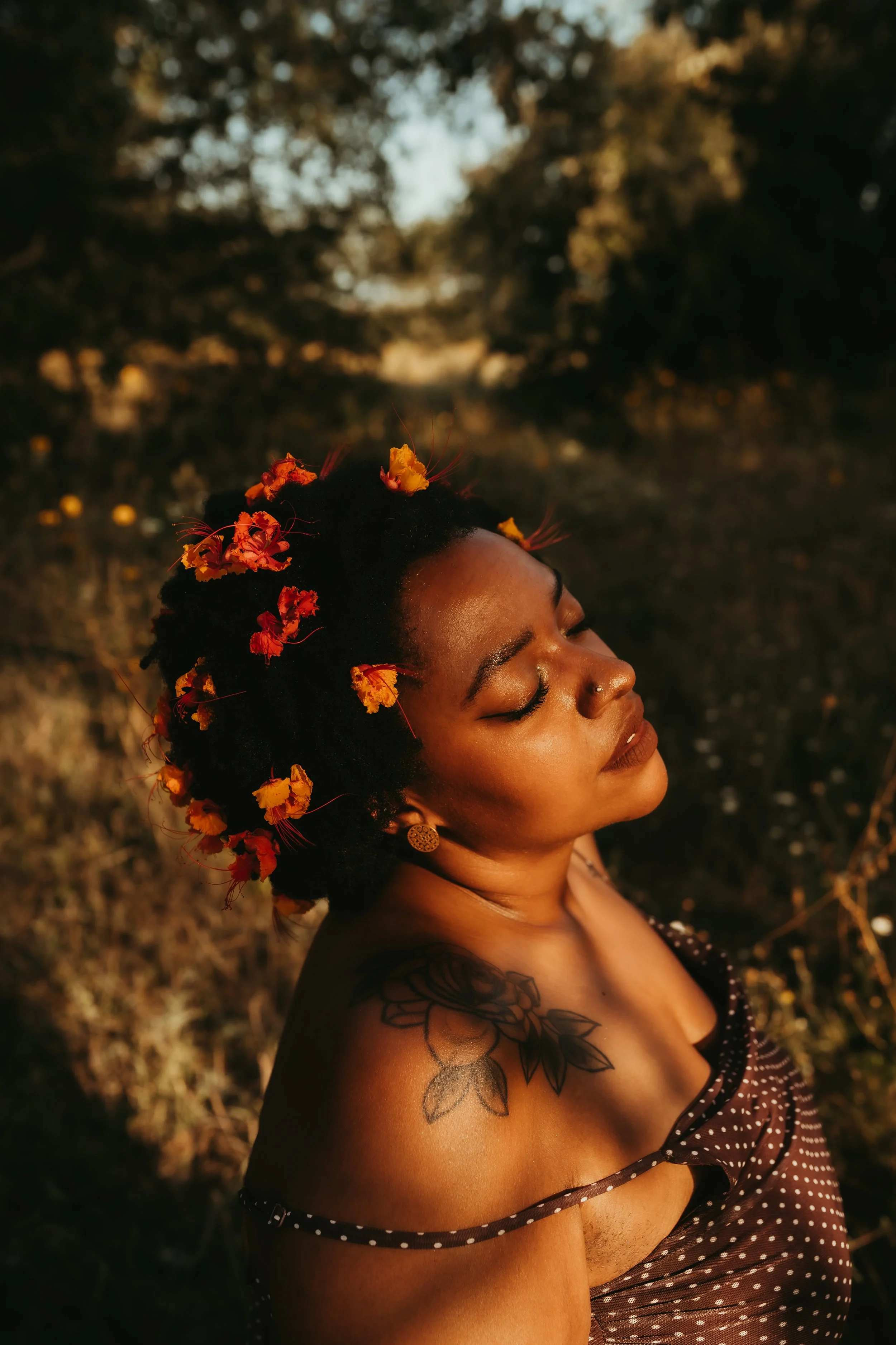 a black woman with orange and yellow flowers in her afro
