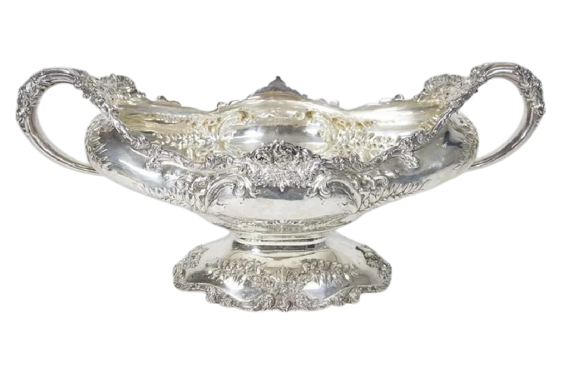 Large antique sterling silver centerpiece bowl with ornate repoussé decoration, scrolling handles, and pedestal base.