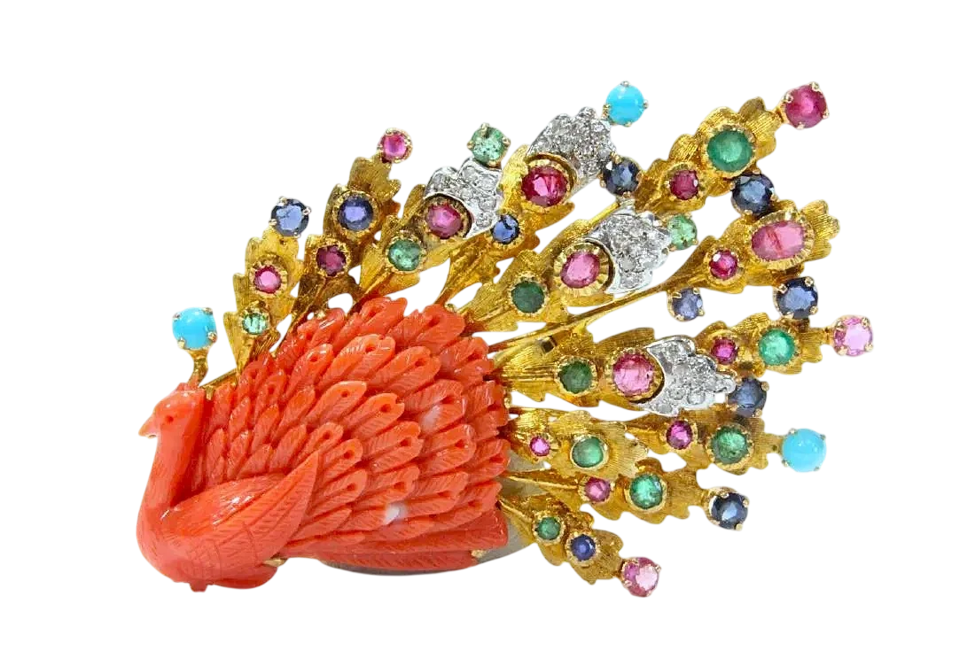 Vintage coral peacock brooch featuring carved coral, diamonds, emeralds, sapphires, and rubies in a gold setting.
