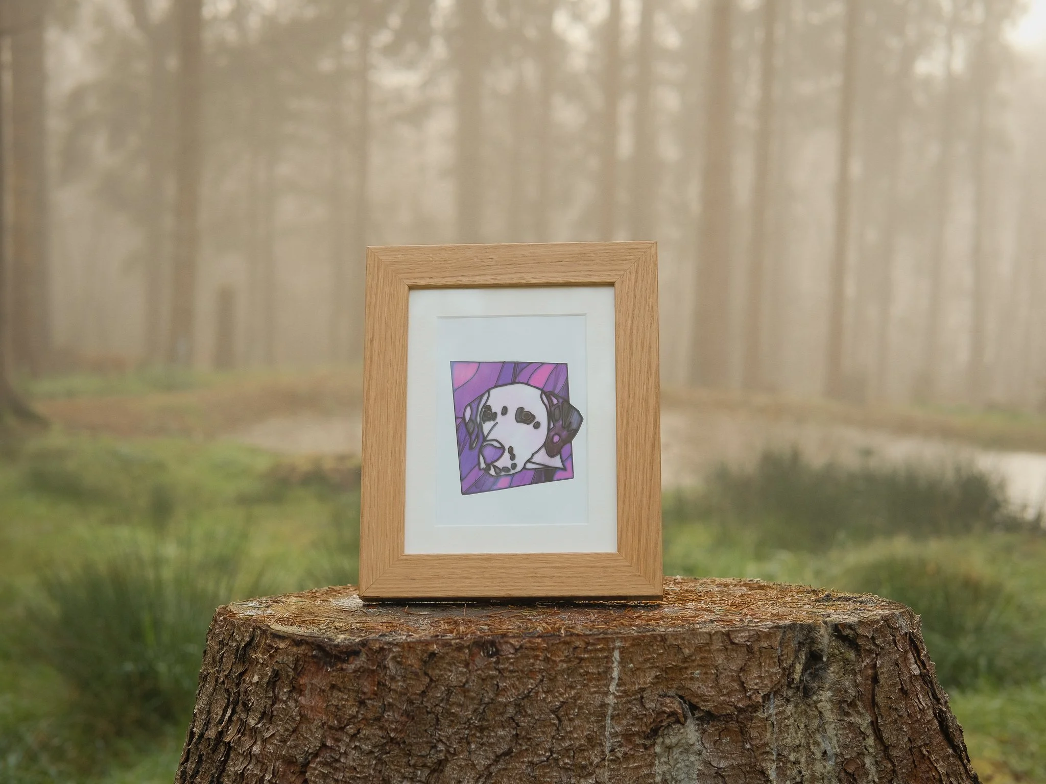 Photograph of a framed illustration of a dog on a tree stump in a foggy forest. A pet memorial product from Fleur Fauna