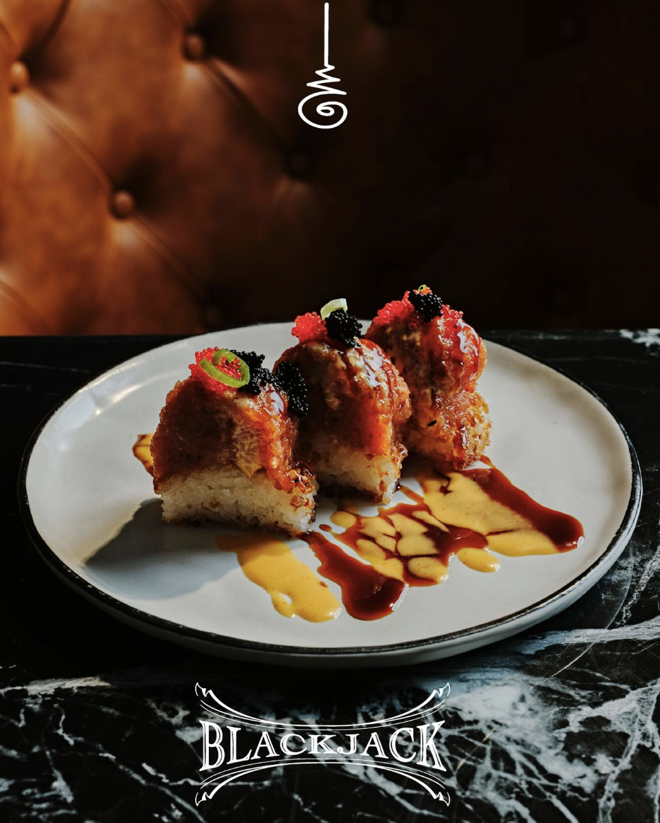 Asian-inspired tapas dish at Blackjack Bar Tapas in Midtown Atlanta featuring crispy rice topped with spicy tuna and sauces on a marble table setting