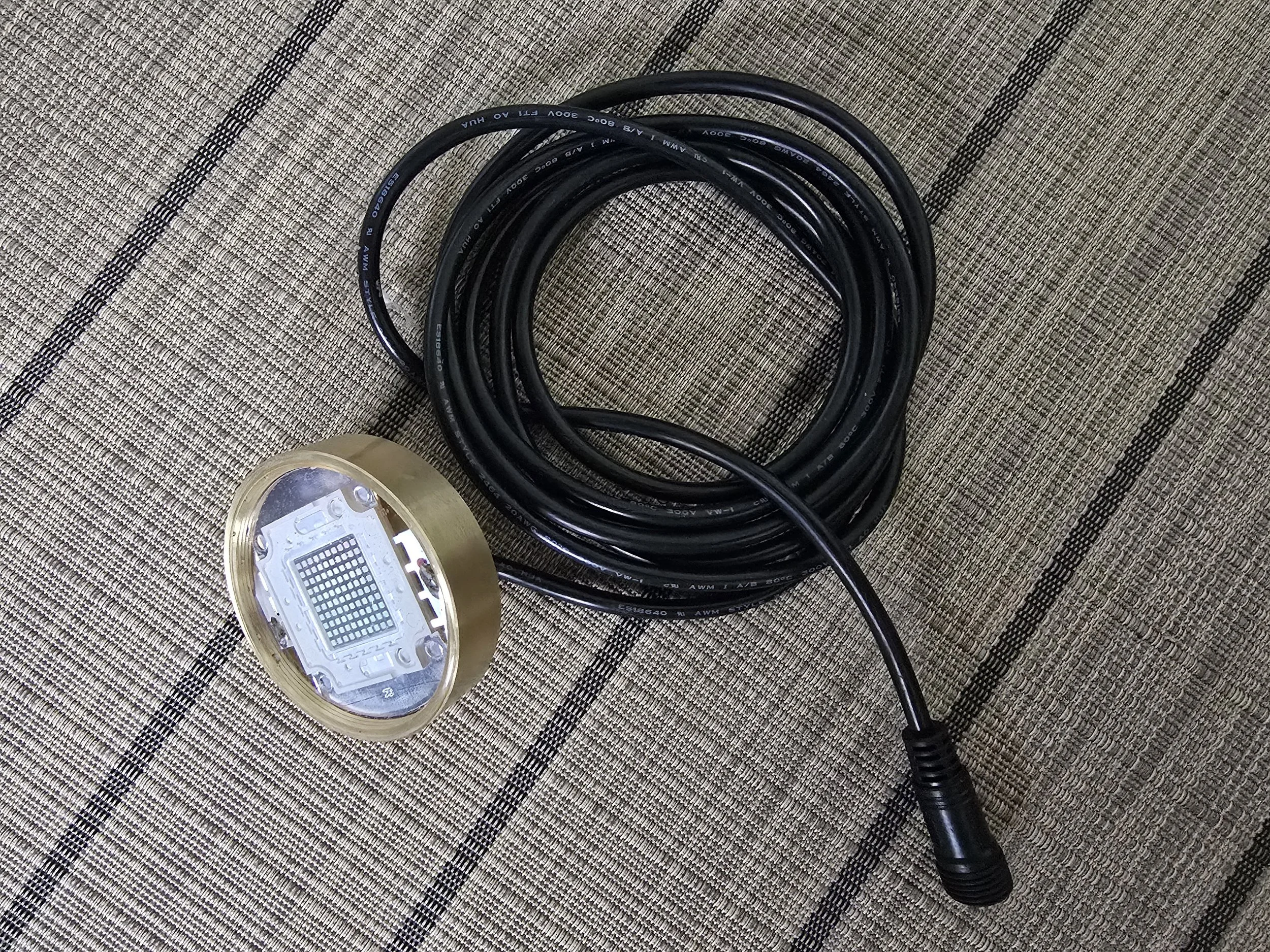 Electrical cable with a metal connector on a striped fabric surface.