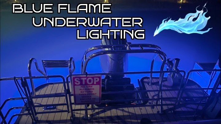 Boat docked at night with blue underwater lighting, a flaming blue flame graphic, and a warning sign on the boat deck.