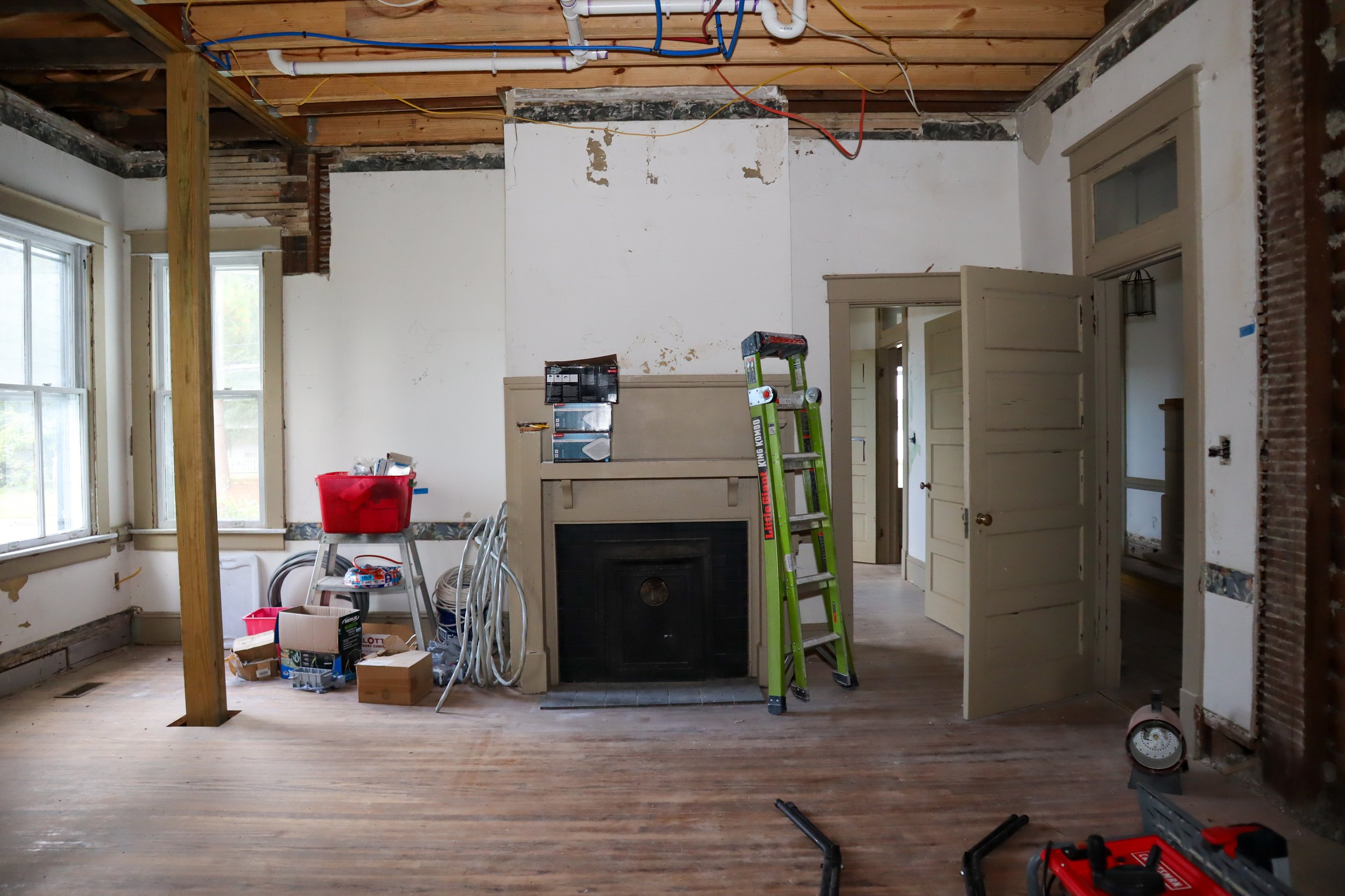 Room under renovation with tools, ladder, and exposed ceiling.
